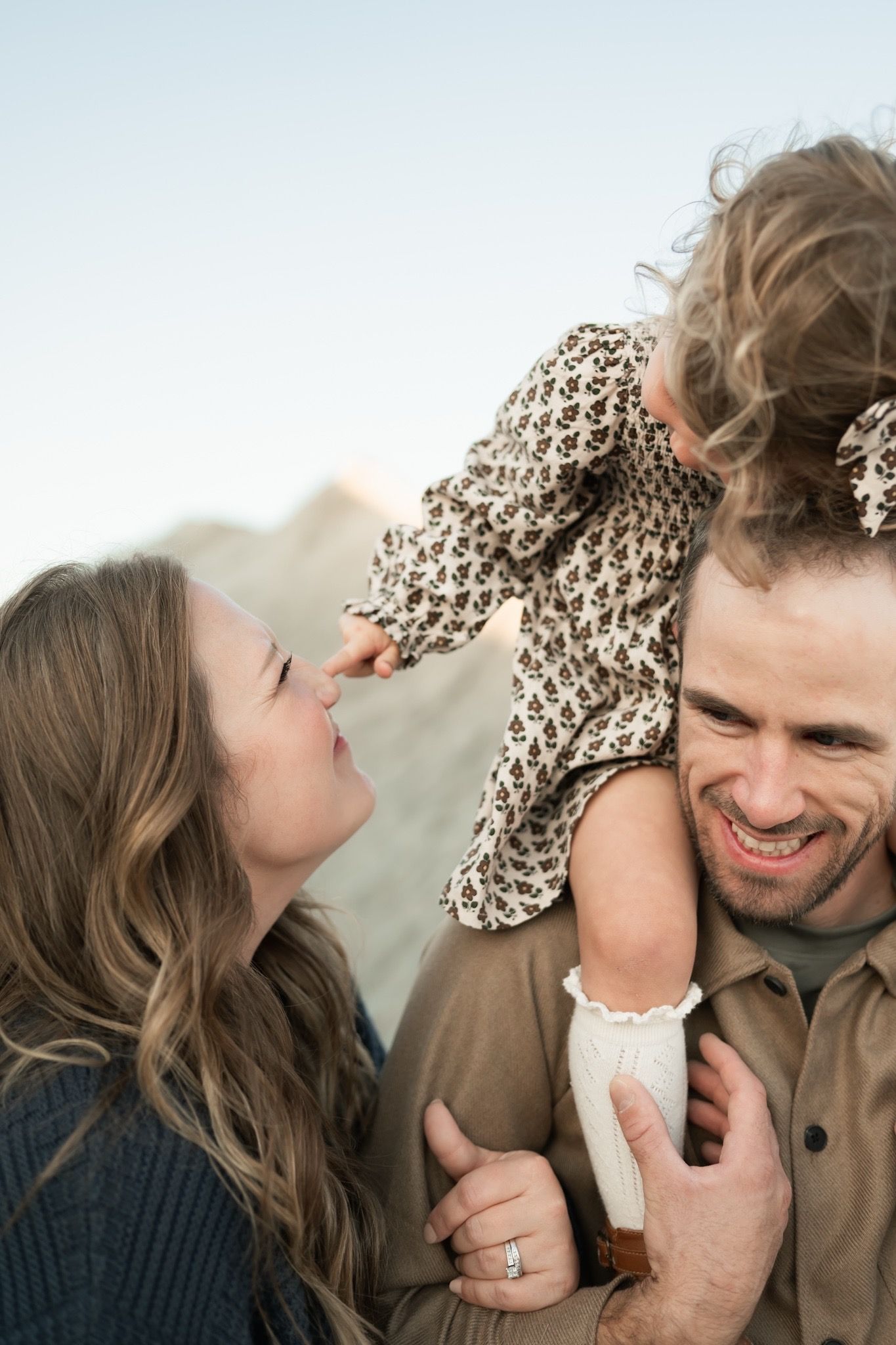 A young family sharing a tender moment together outdoors in a sunlit field during golden hour.