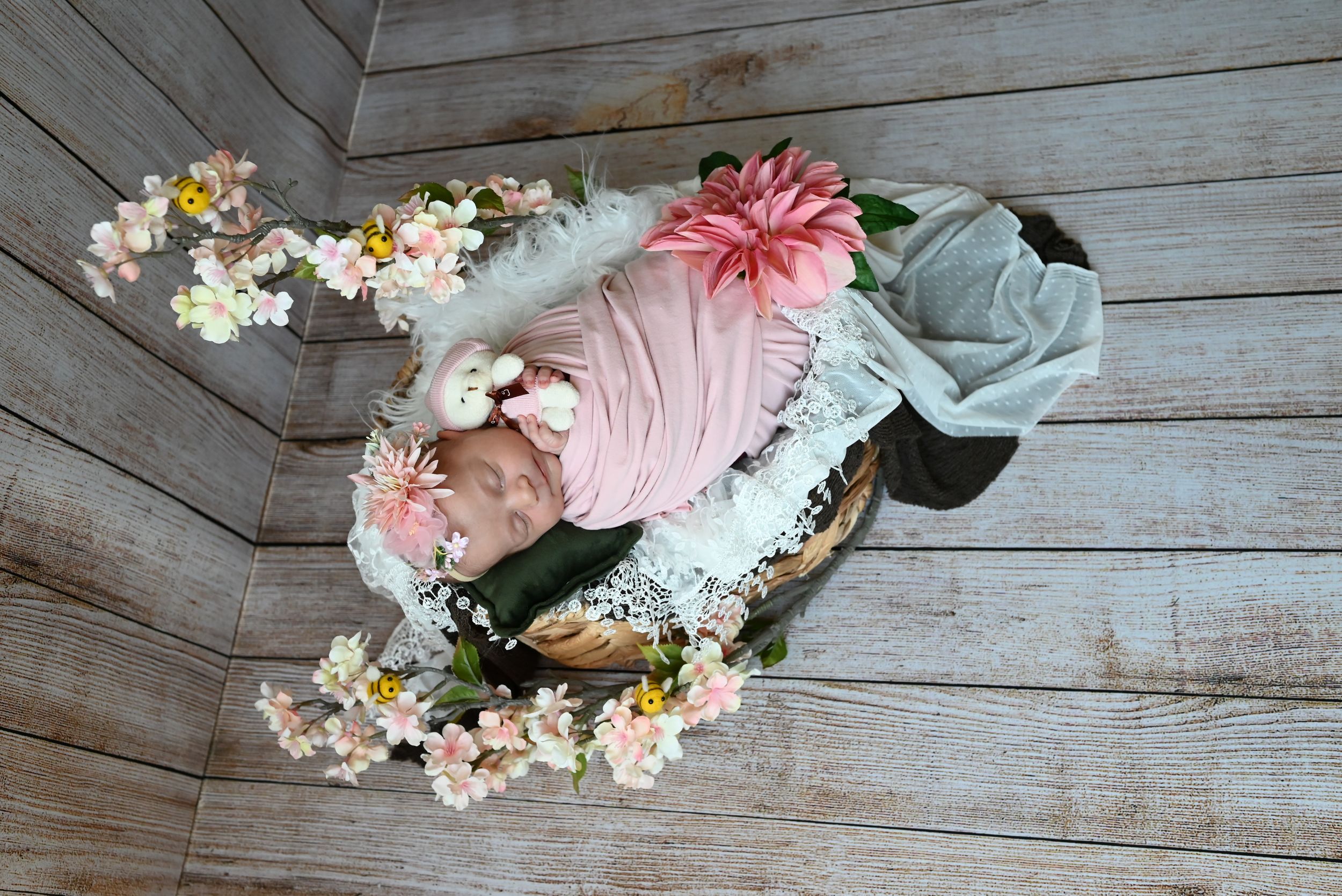 Pink ballet pointe shoes decorated with delicate floral arrangements rest on rustic wooden floorboards.