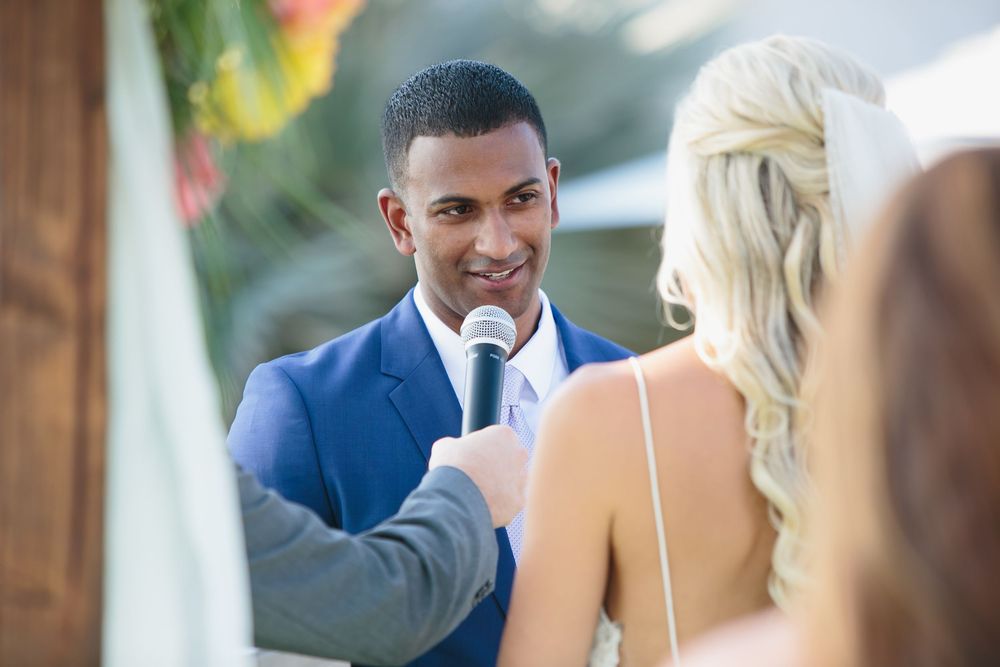 Bride and groom share a joyful moment during their outdoor wedding ceremony under natural sunlight.