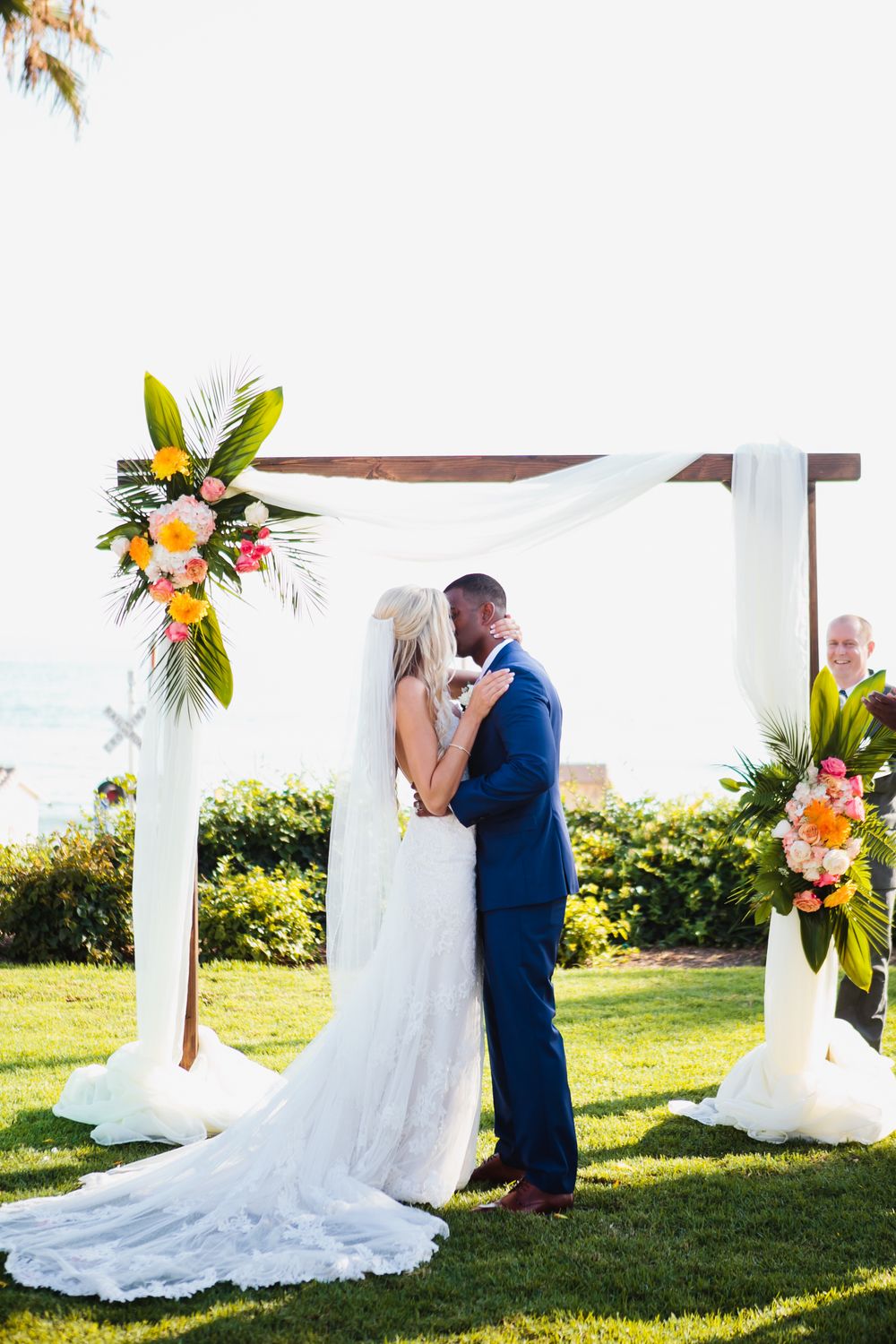 Bride and groom first kiss at Ole Hanson Beach Club in San Clemente during wedding ceremony overlooking the ocean.