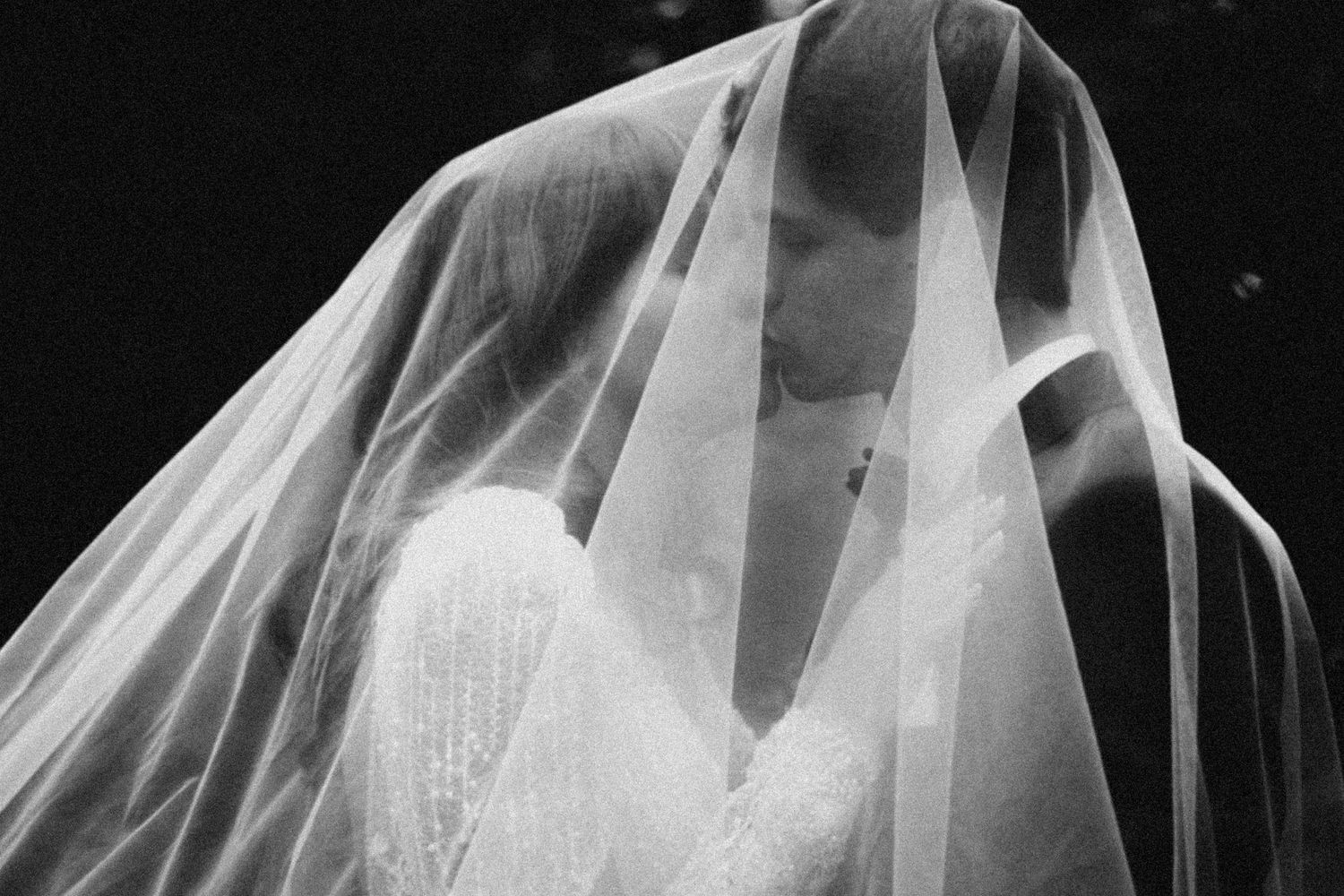 Close-up black and white photograph showing delicate bridal veil draping over a sweetheart neckline wedding dress.