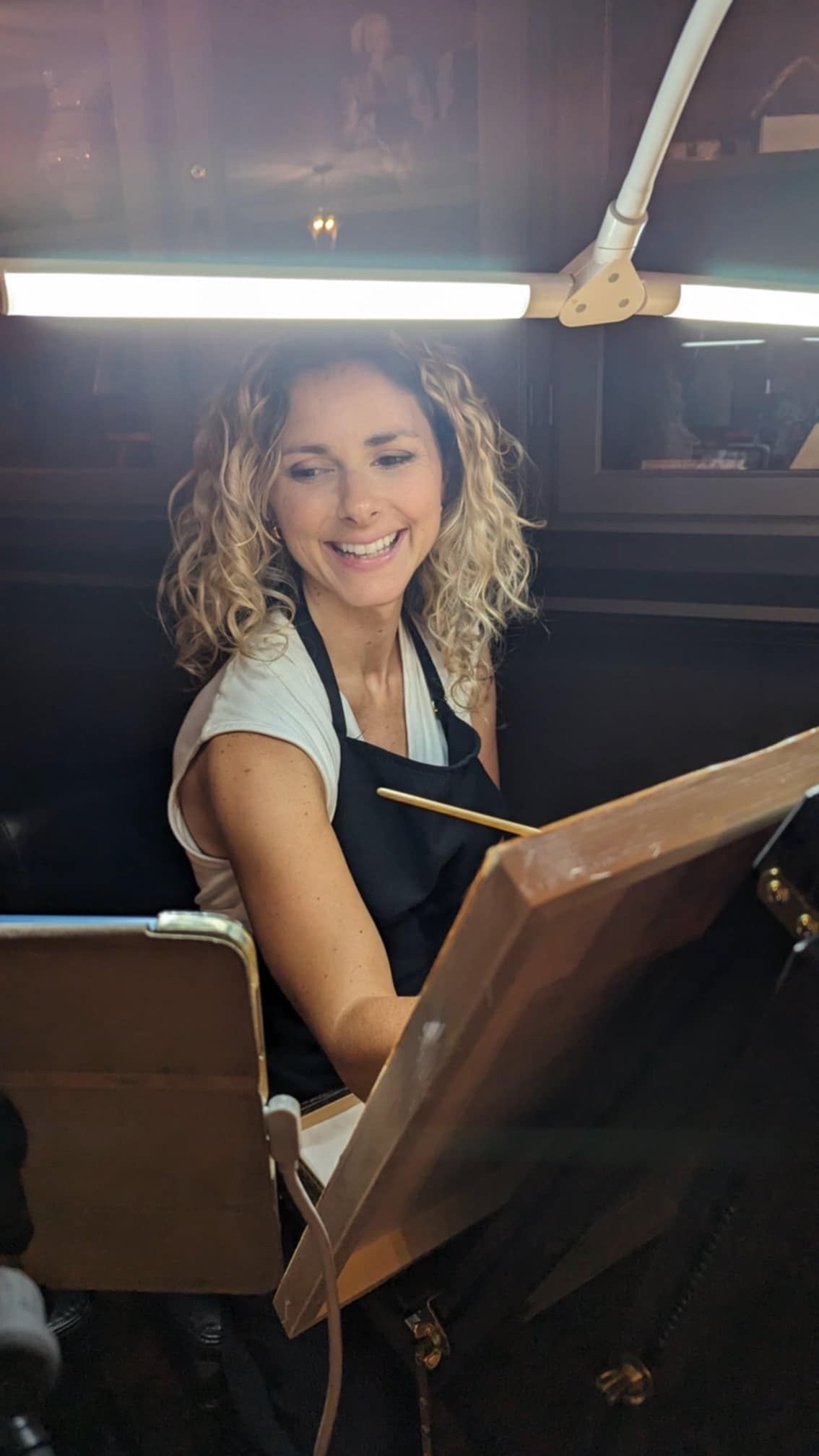 Someone looks at a menu while sitting at a dimly lit restaurant table, appearing happy and engaged.