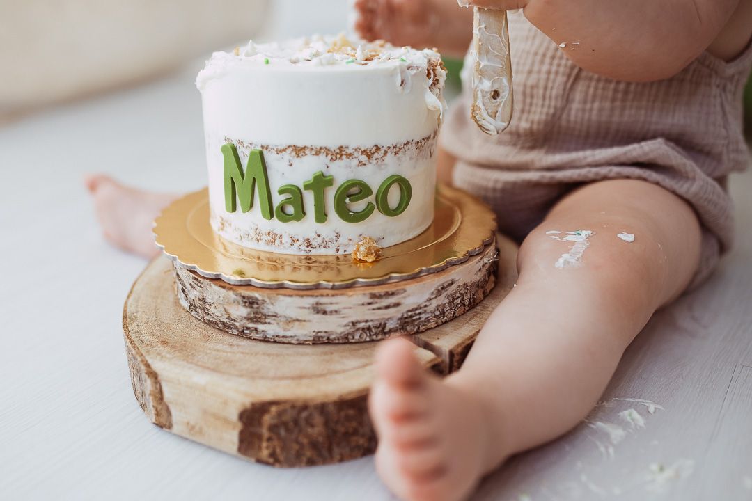 Cake smash photo session setup with rustic wooden elements and green balloons.