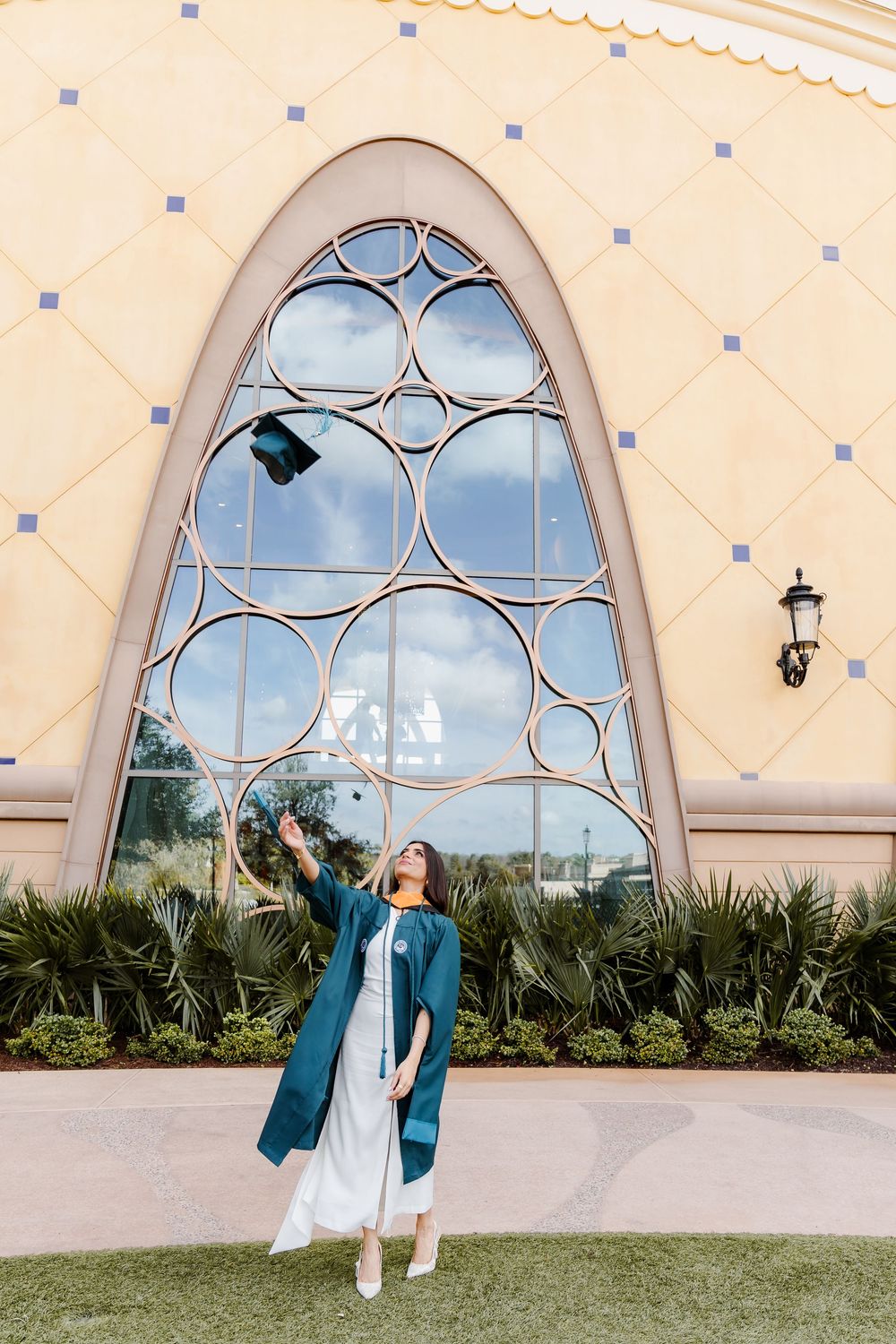 A series of photos showing someone in a white dress and teal jacket posing in front of arched windows with ornate details.