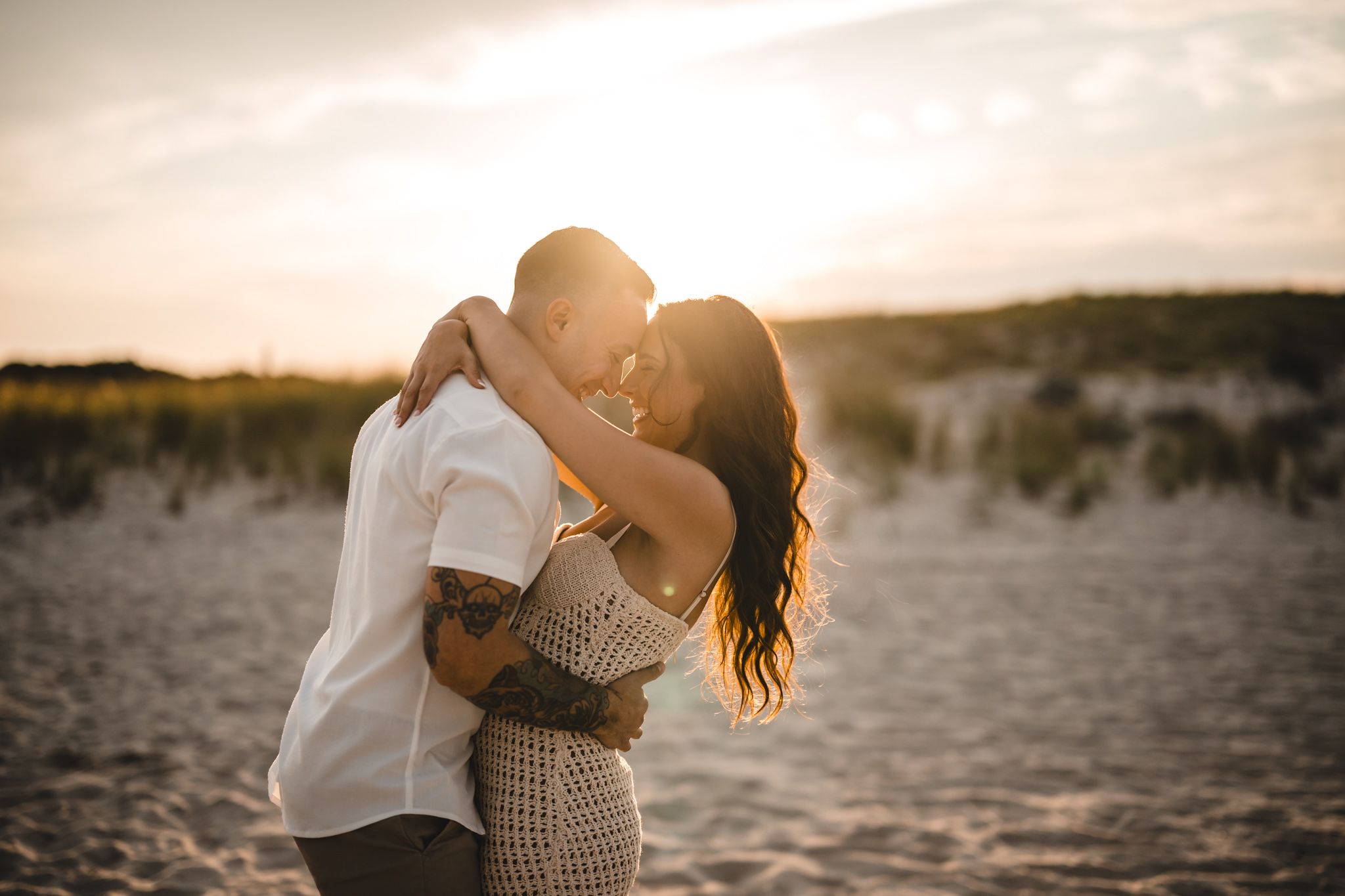 Romantic beach photoshoot with couple dancing in warm evening light.