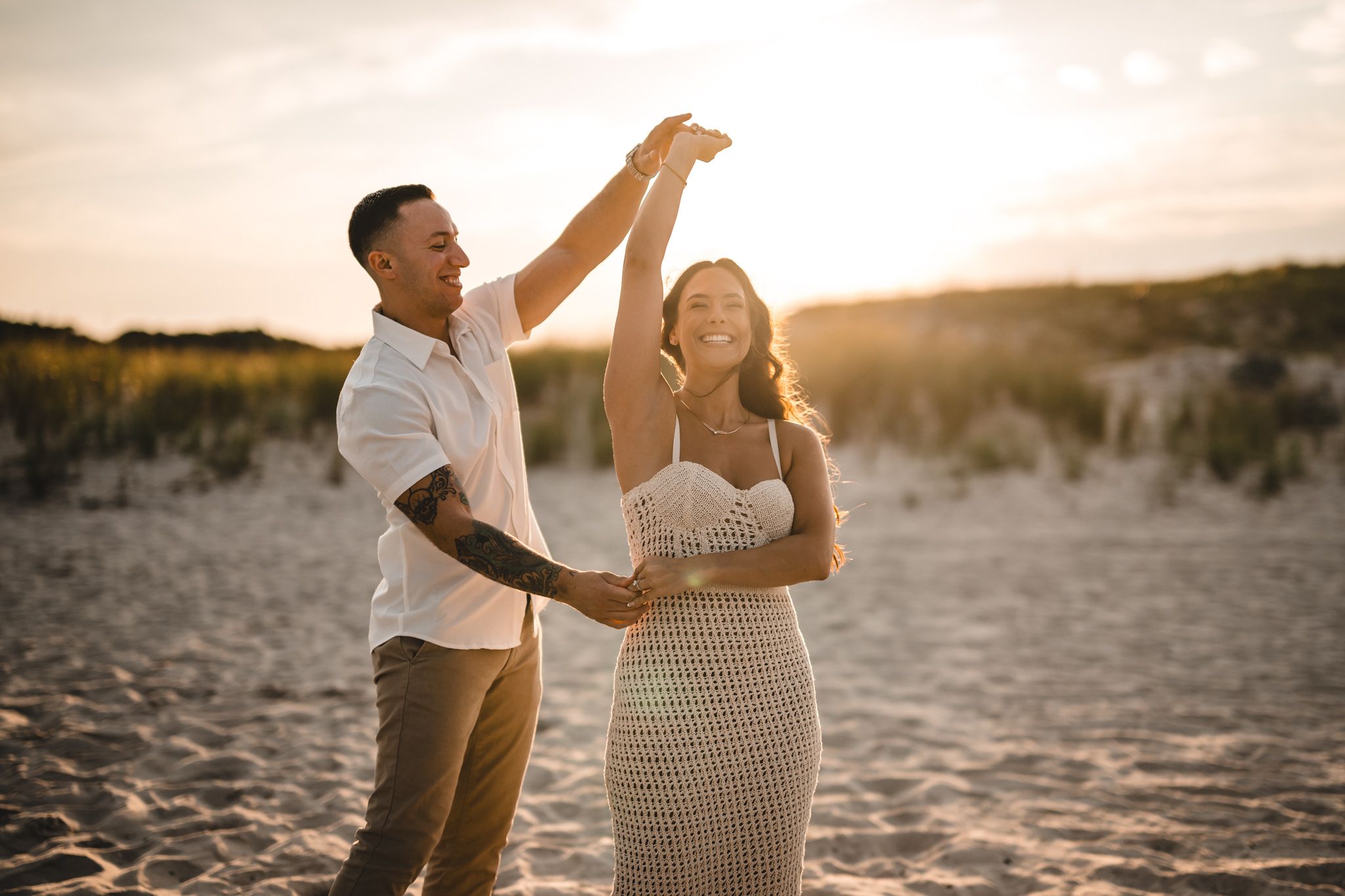 Couple sharing joyful moment while dancing together on beach at sunset.