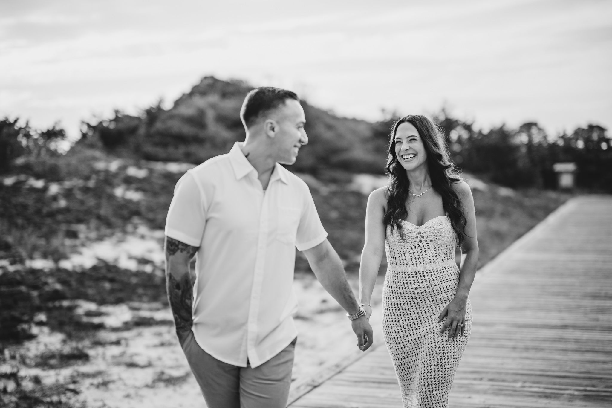 A couple playfully interacts on a coastal boardwalk during a photo session.