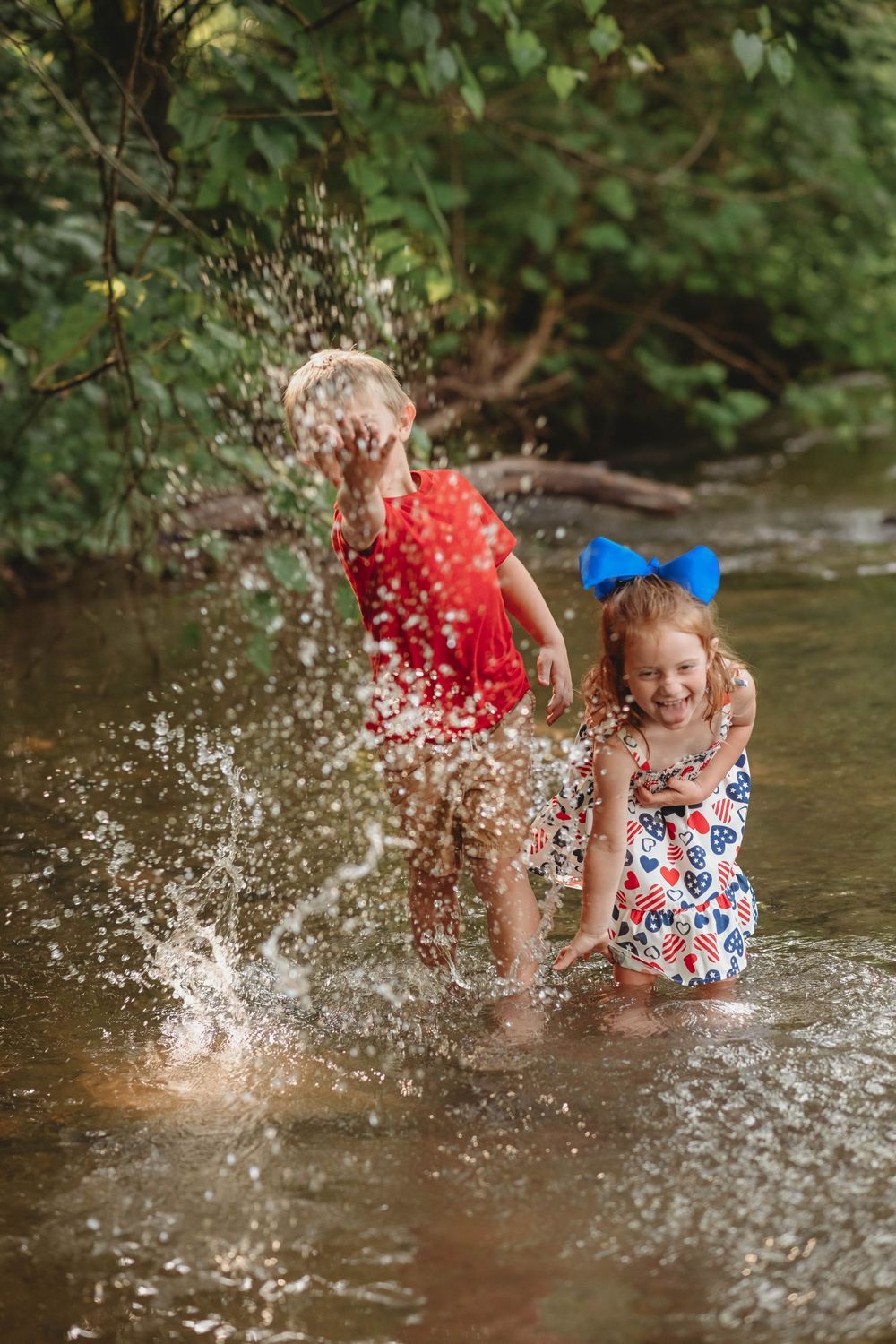 Joyful water splashing creates dramatic spray effects during a creek photo session.
