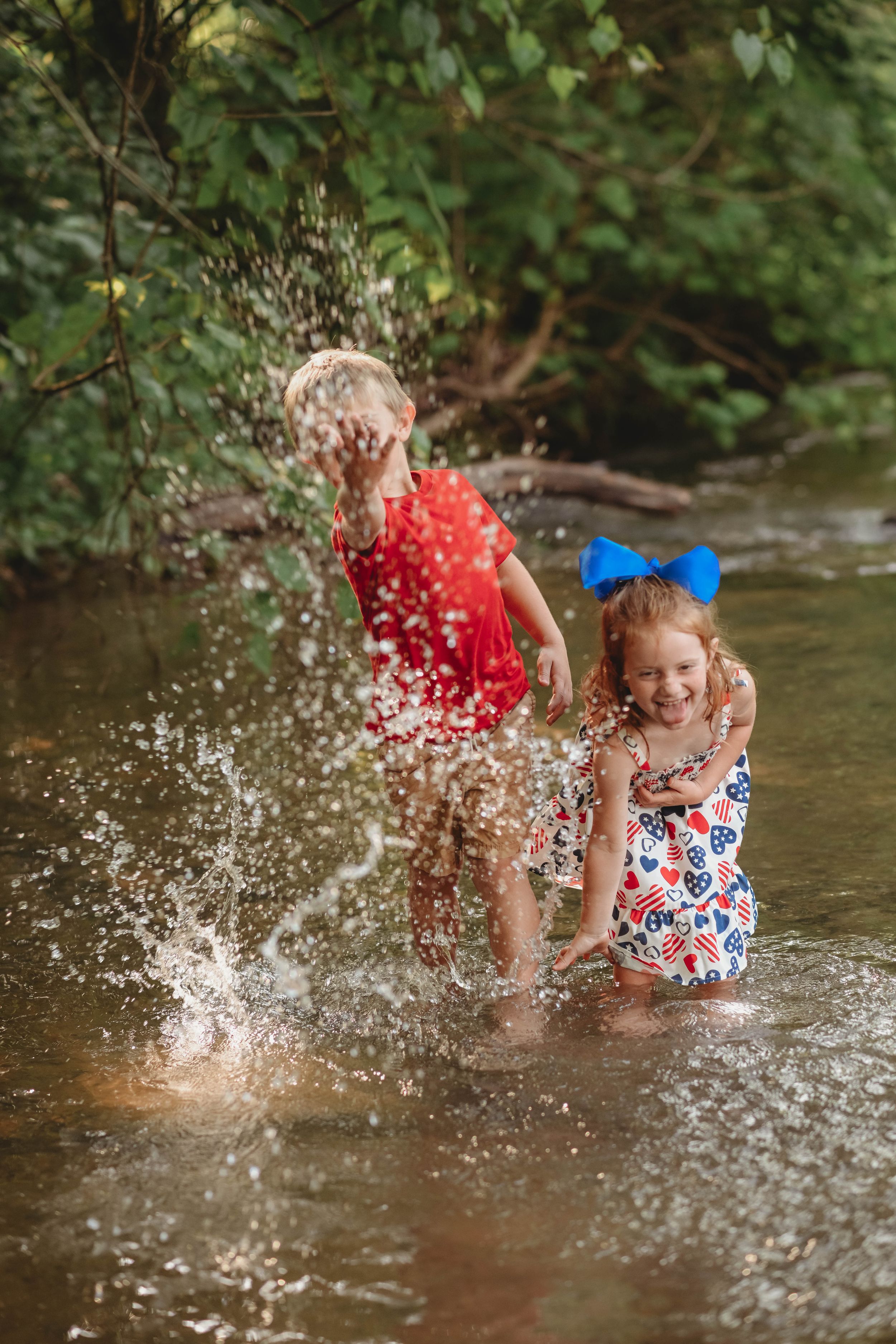 Joyful water splashing creates dramatic spray effects during a creek photo session.