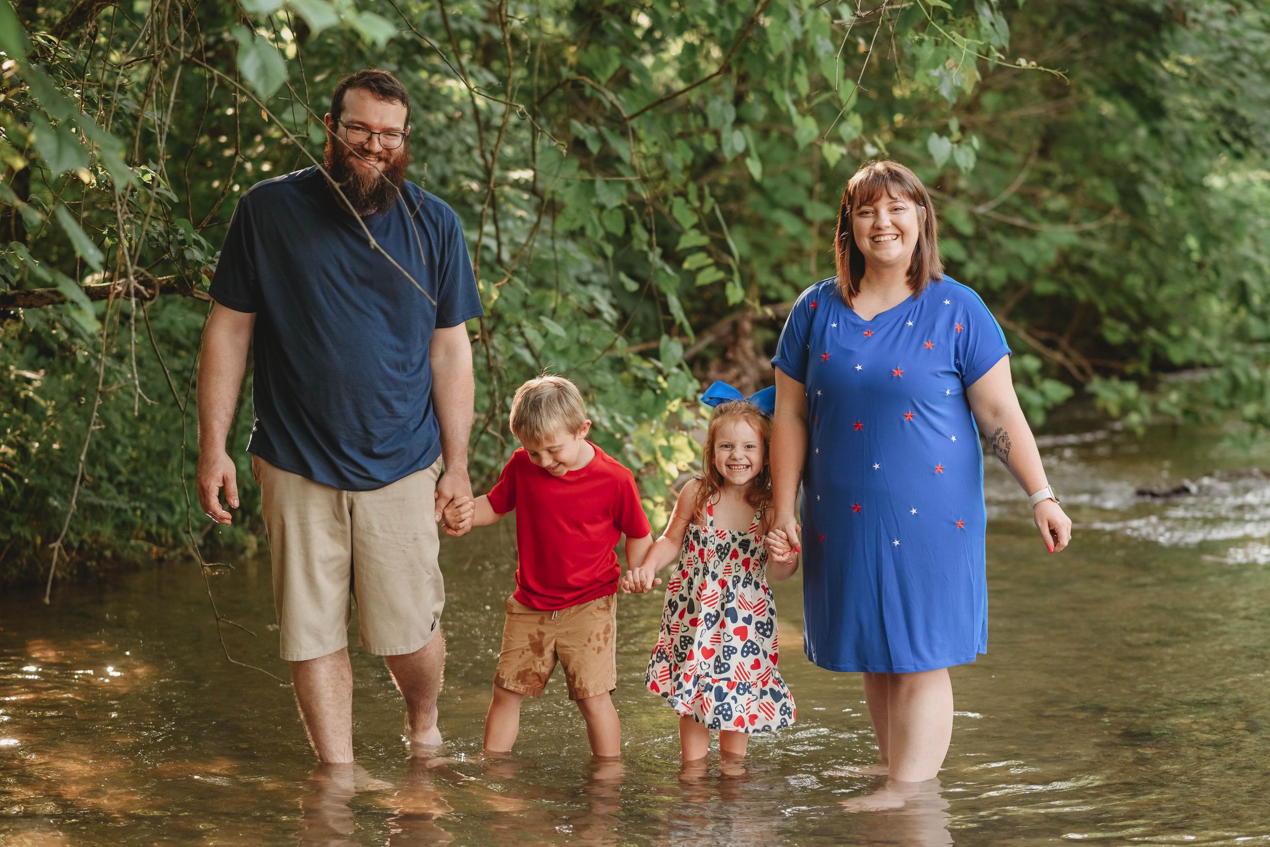 A family splashes and plays together in a shallow creek on a summer day.