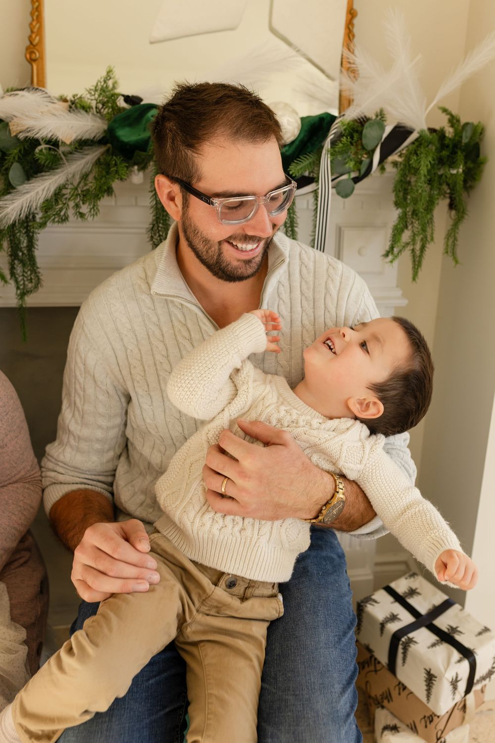 A series of playful interactions between parent and child wearing cream sweaters against a wall decorated with greenery.