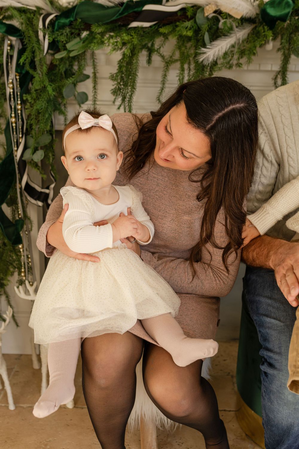 Four connected photos show a baby in a white dress being held in various poses against a light background with greenery.