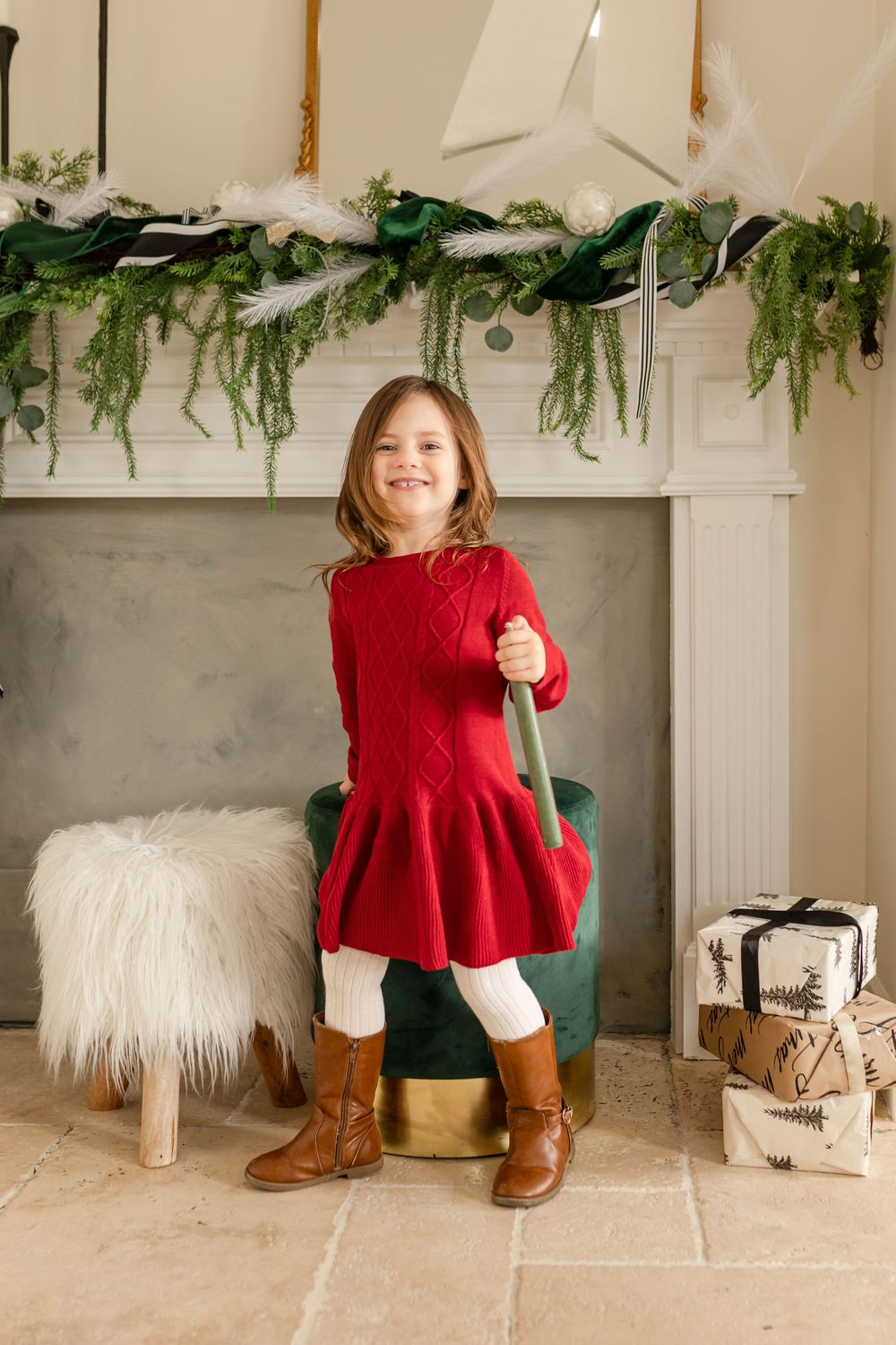 A decorated fireplace mantel with greenery and white stars serves as a festive holiday backdrop.