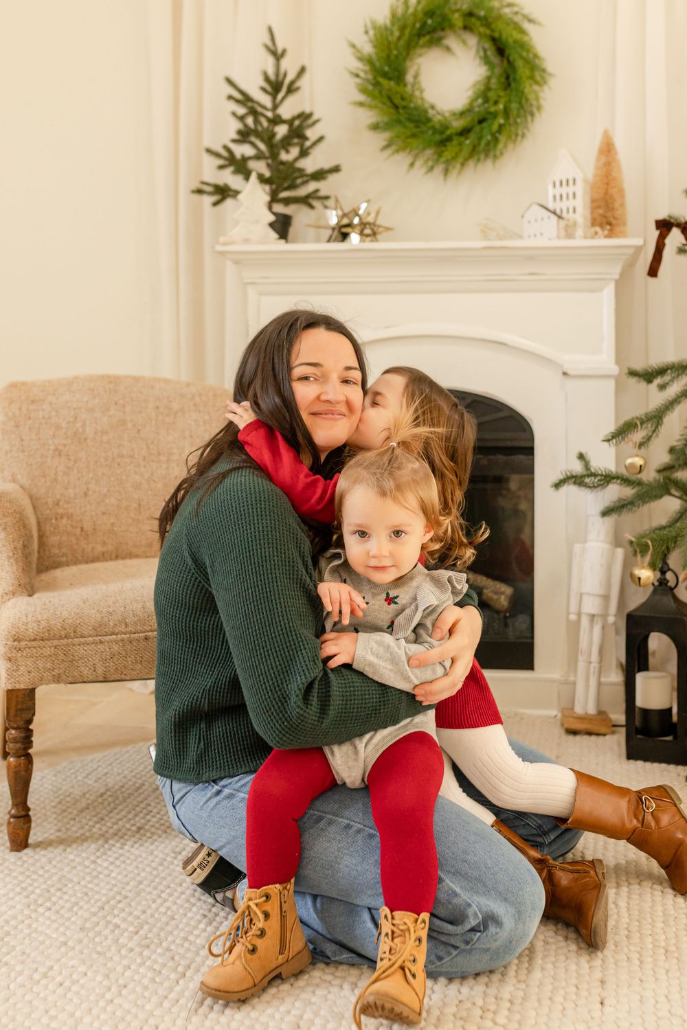 Cozy holiday living room with green wreaths, white fireplace mantel, and loving family moments on beige sofa.