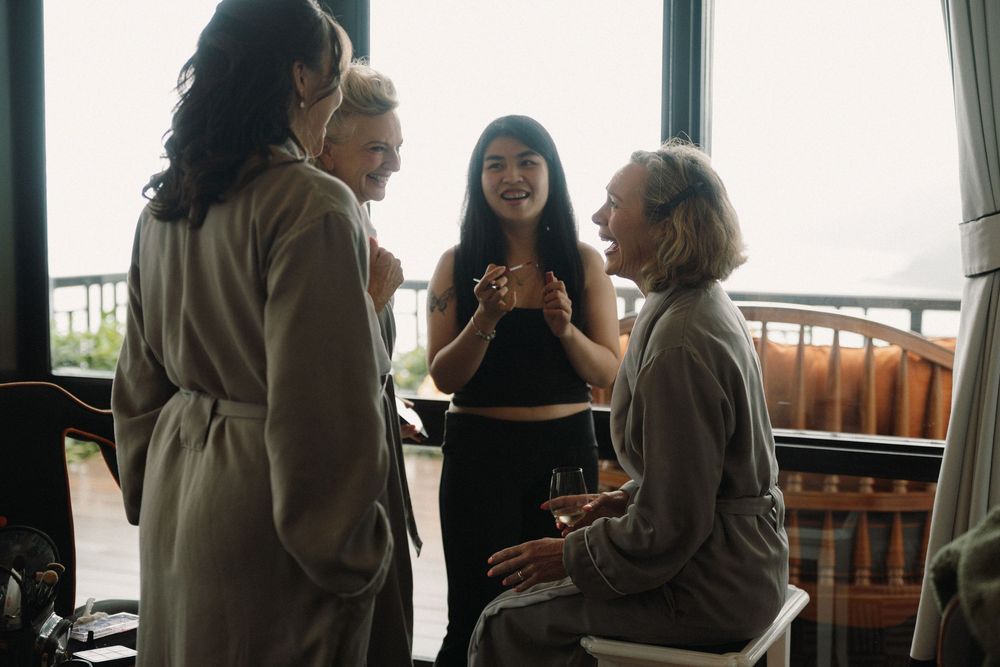 Group of people chatting by large windows in casual business setting.