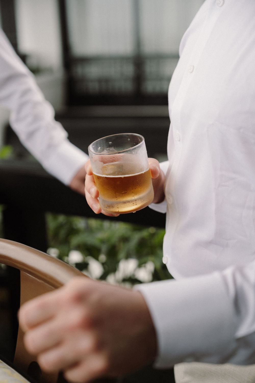 Close-up of someone holding a glass of amber-colored beverage during a formal event.
