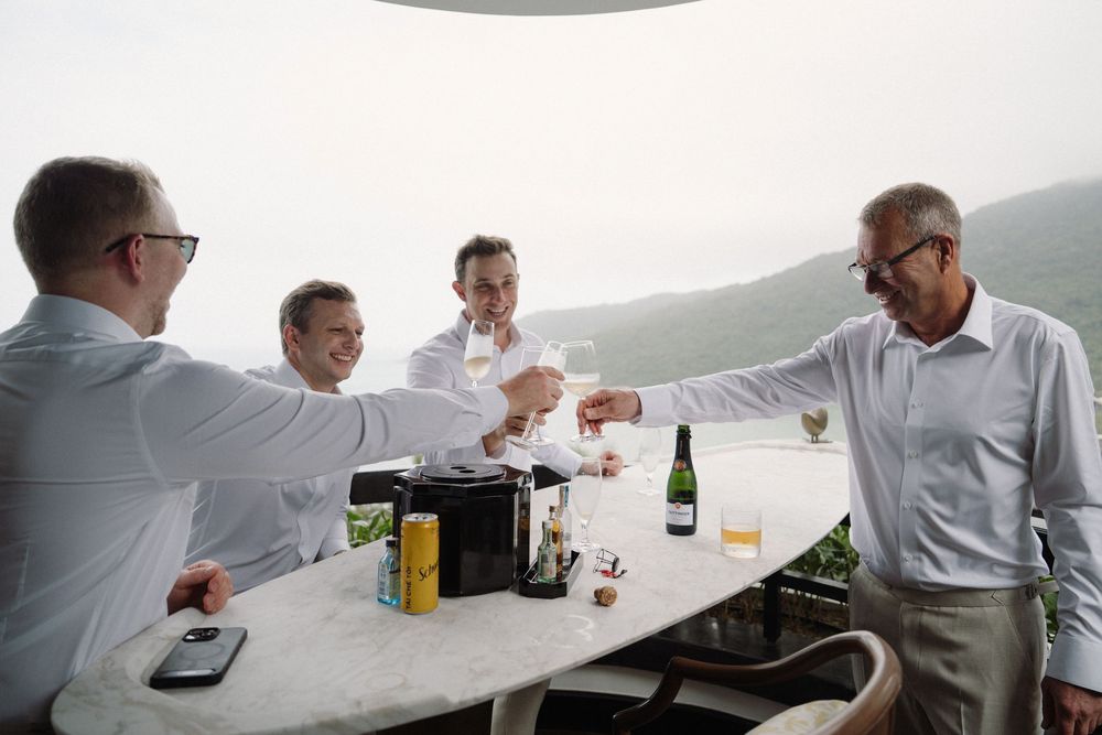 Wedding party gathered around a long table with drinks and refreshments.