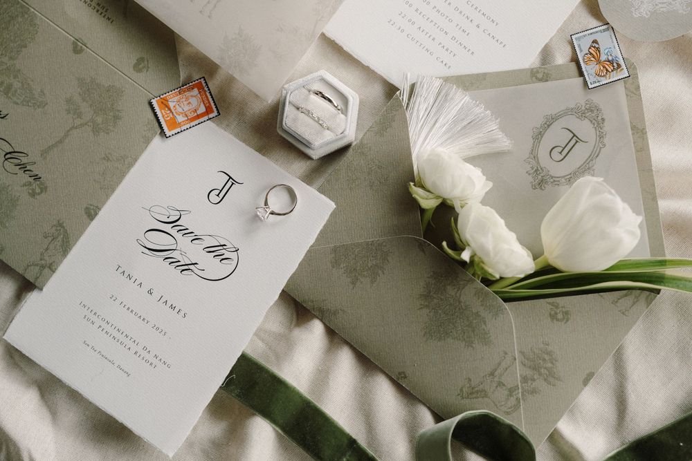 Wedding stationery and invitation cards elegantly arranged with white roses on a textured gray surface.