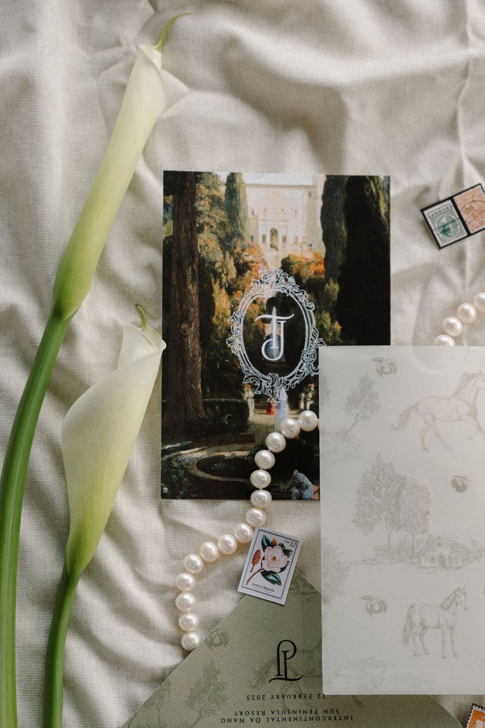 Wedding details including calla lilies, pearl necklace, and photos arranged on white fabric.