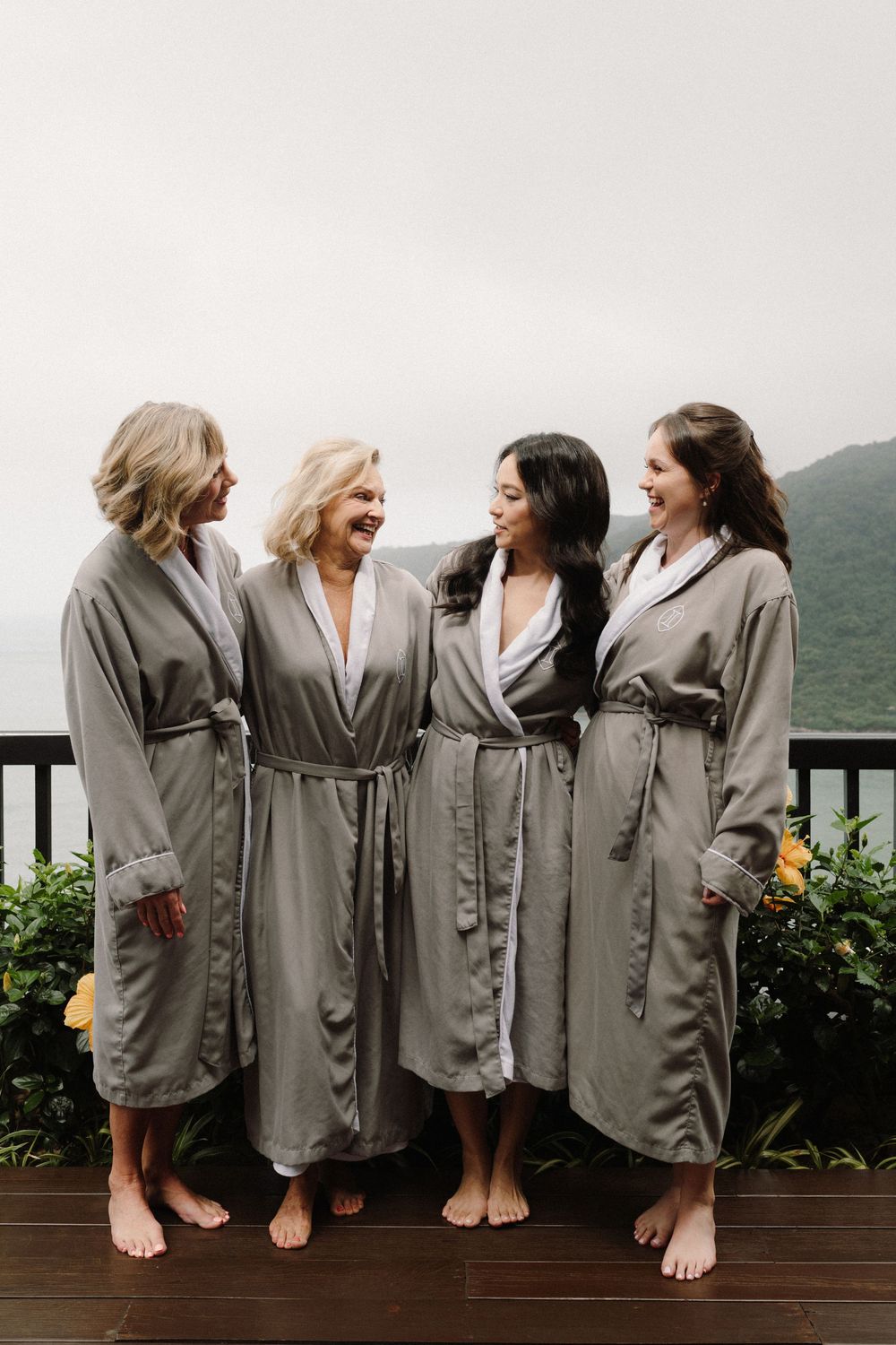 Five people in matching gray robes sit on a deck overlooking a mountain landscape.