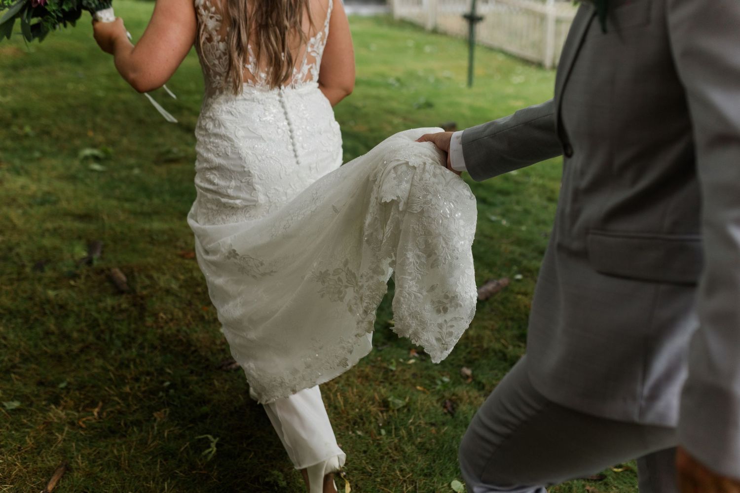 A couple outdoors showcases a playful dance move where a bride in white dress is being dipped by her partner in grey.