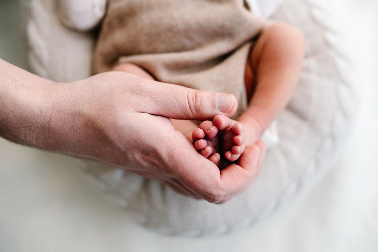 Two hands gently cupped together holding tiny newborn feet taken during a in home Melbourne newborn photography session by Pei A Photography