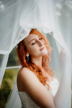 Ethereal bridal portrait through flowing white veil with soft natural lighting.