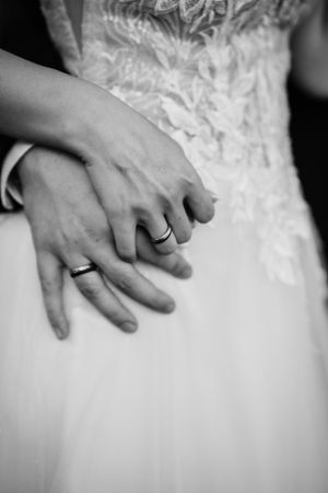 Close-up black and white detail shot of delicate lace pattern on a white wedding dress.
