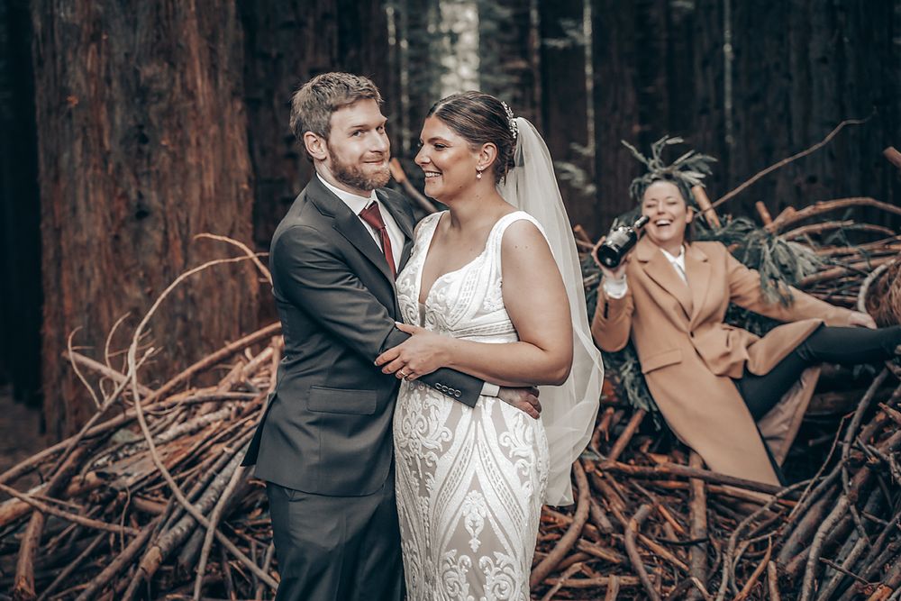 Elegant couple shares romantic moments among tall trees during sunset wedding photography session.