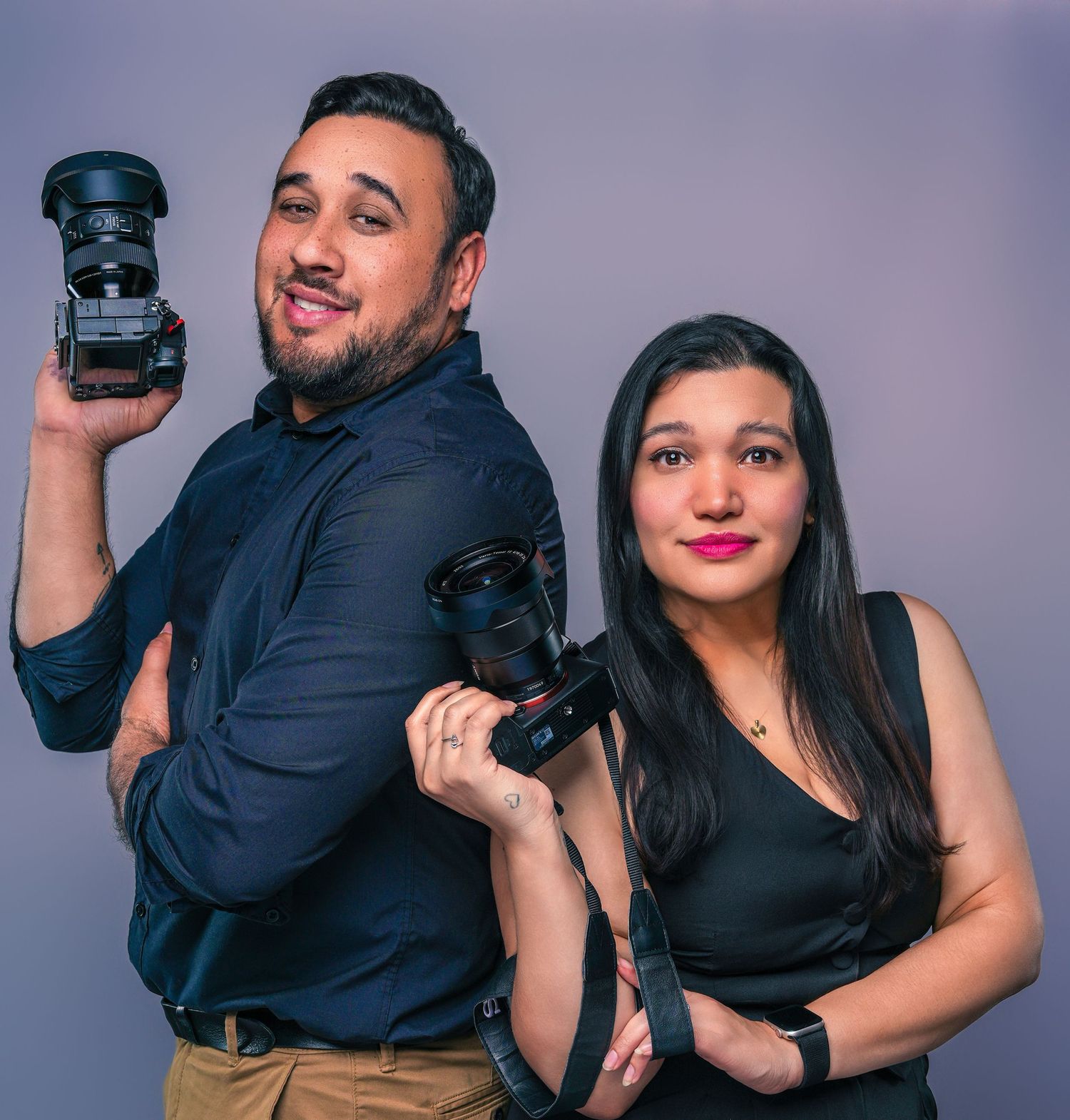 Two photographers holding professional cameras pose together through a series of fun and playful positions.