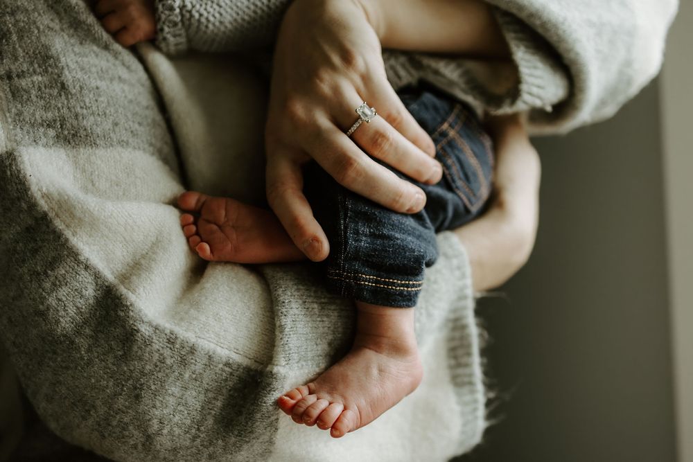 Close-up of tiny baby feet being held by gentle hands in soft lighting.