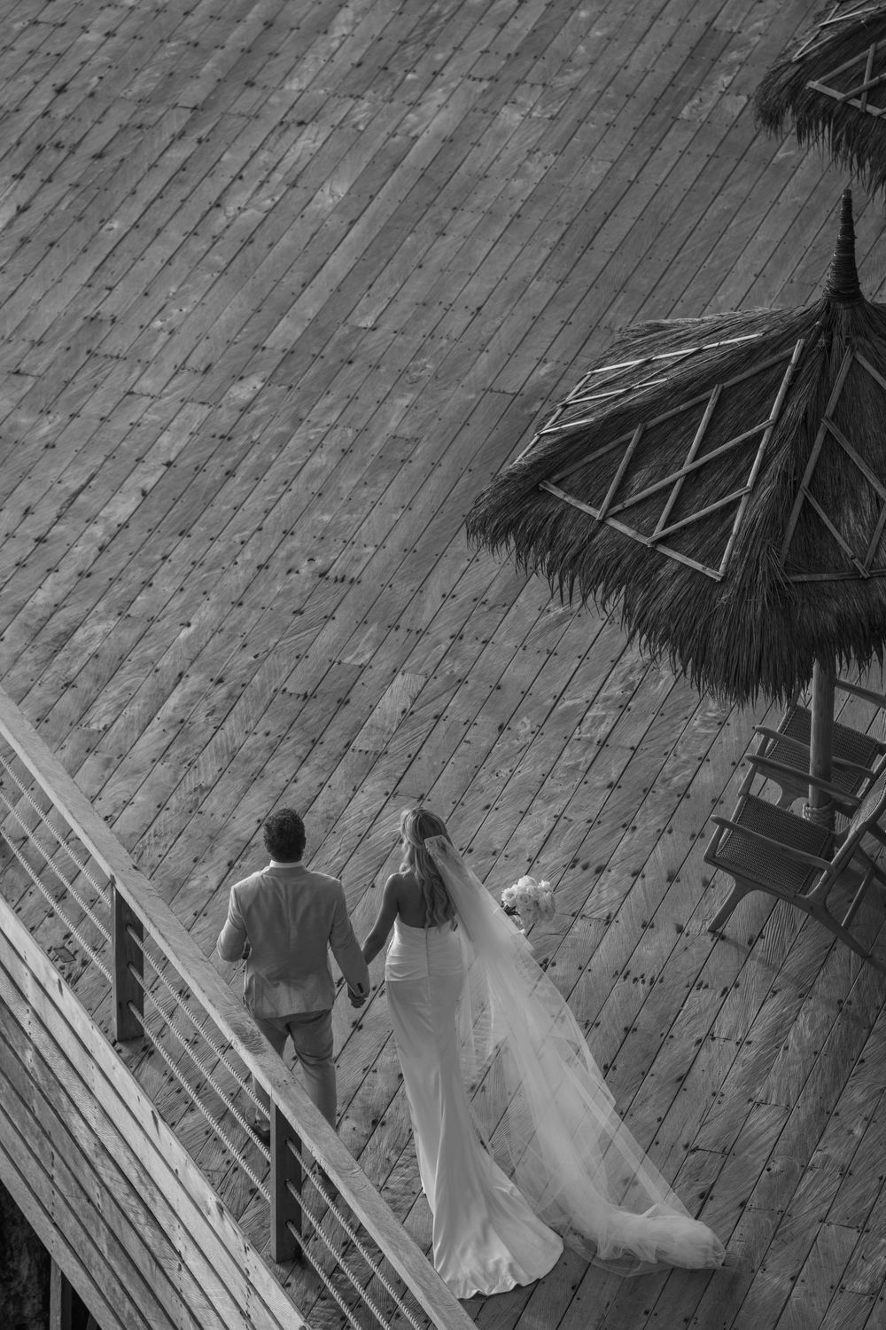 Black and white overhead view of people walking across a patterned cobblestone or brick courtyard.