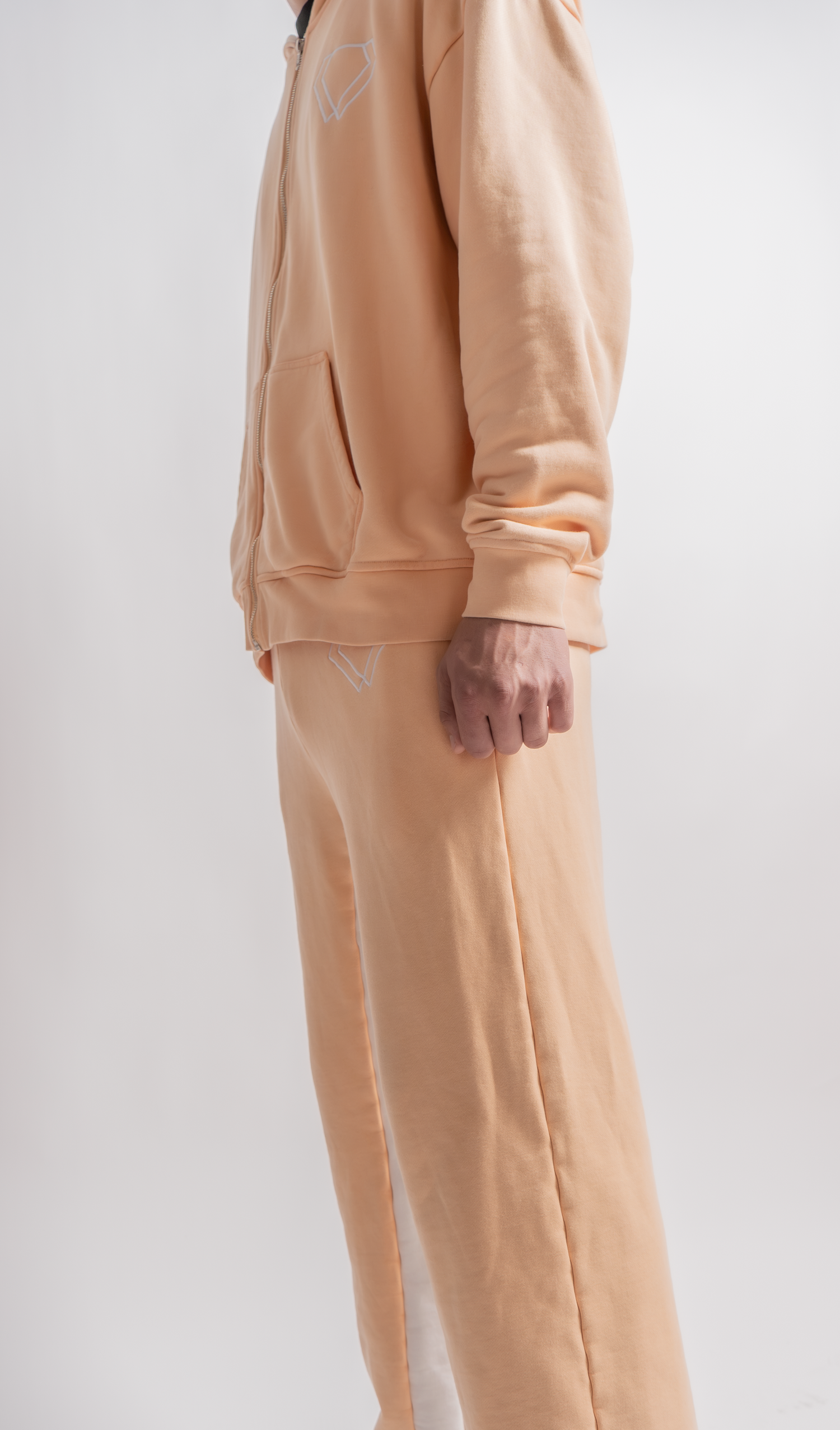 Close-up view of a cozy peach-colored sweatsuit set showing the relaxed fit and soft fabric texture against white backdrop.