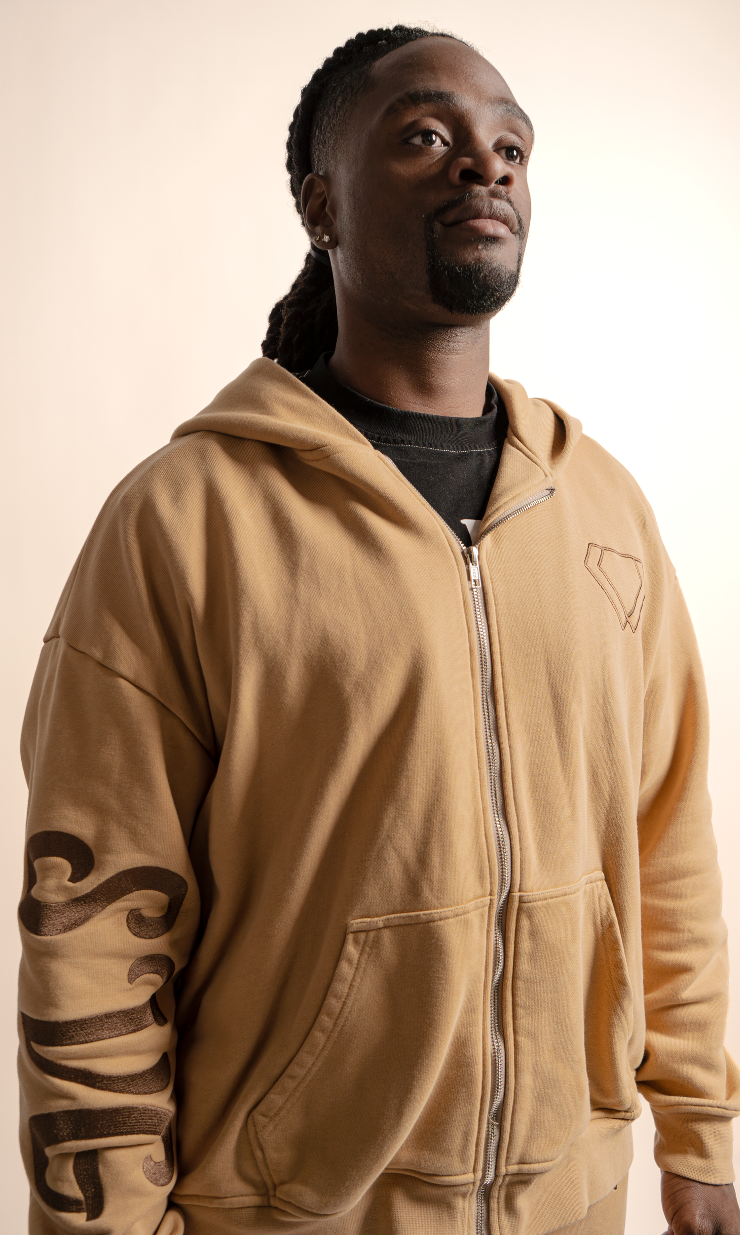 Person wearing a tan zip-up hoodie sweatshirt shown from different angles against a light background.