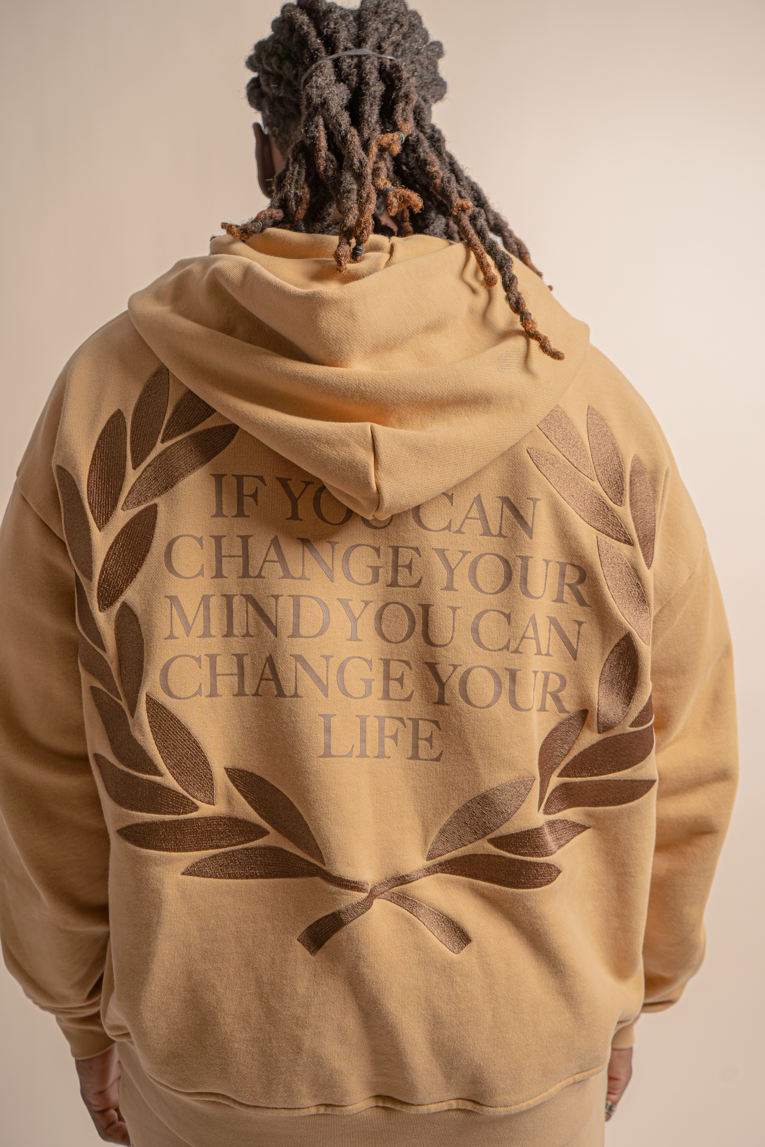 Beige hoodie sweatshirt with 'If You Can Change Your Mind You Can Change Your Life' text and leaf design on back.