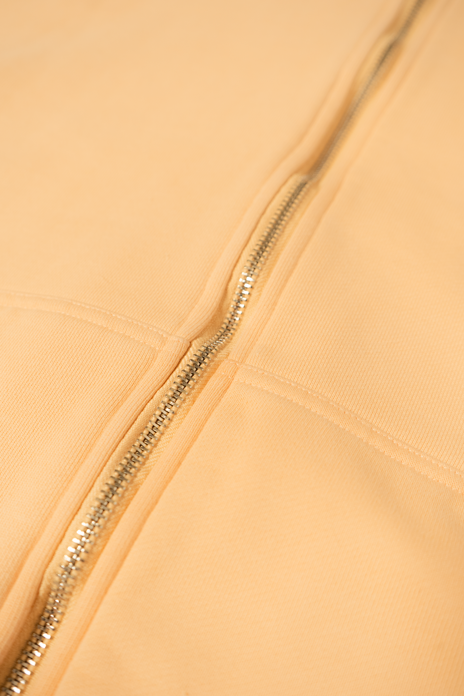 A close-up view of white fabric with metal zipper details creating a minimalist textural pattern.
