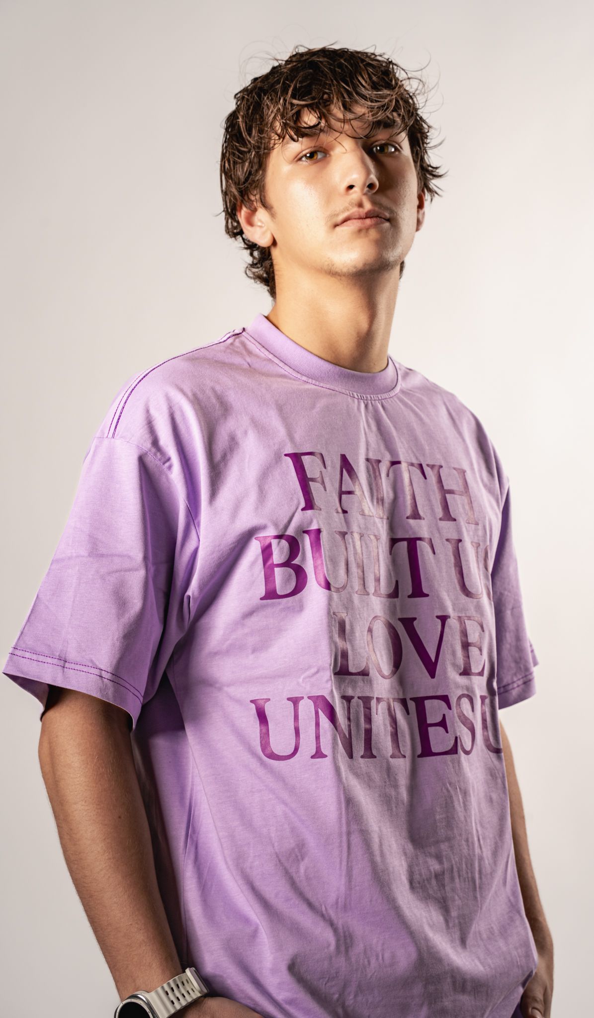 Person wearing a purple t-shirt with text design against white background.