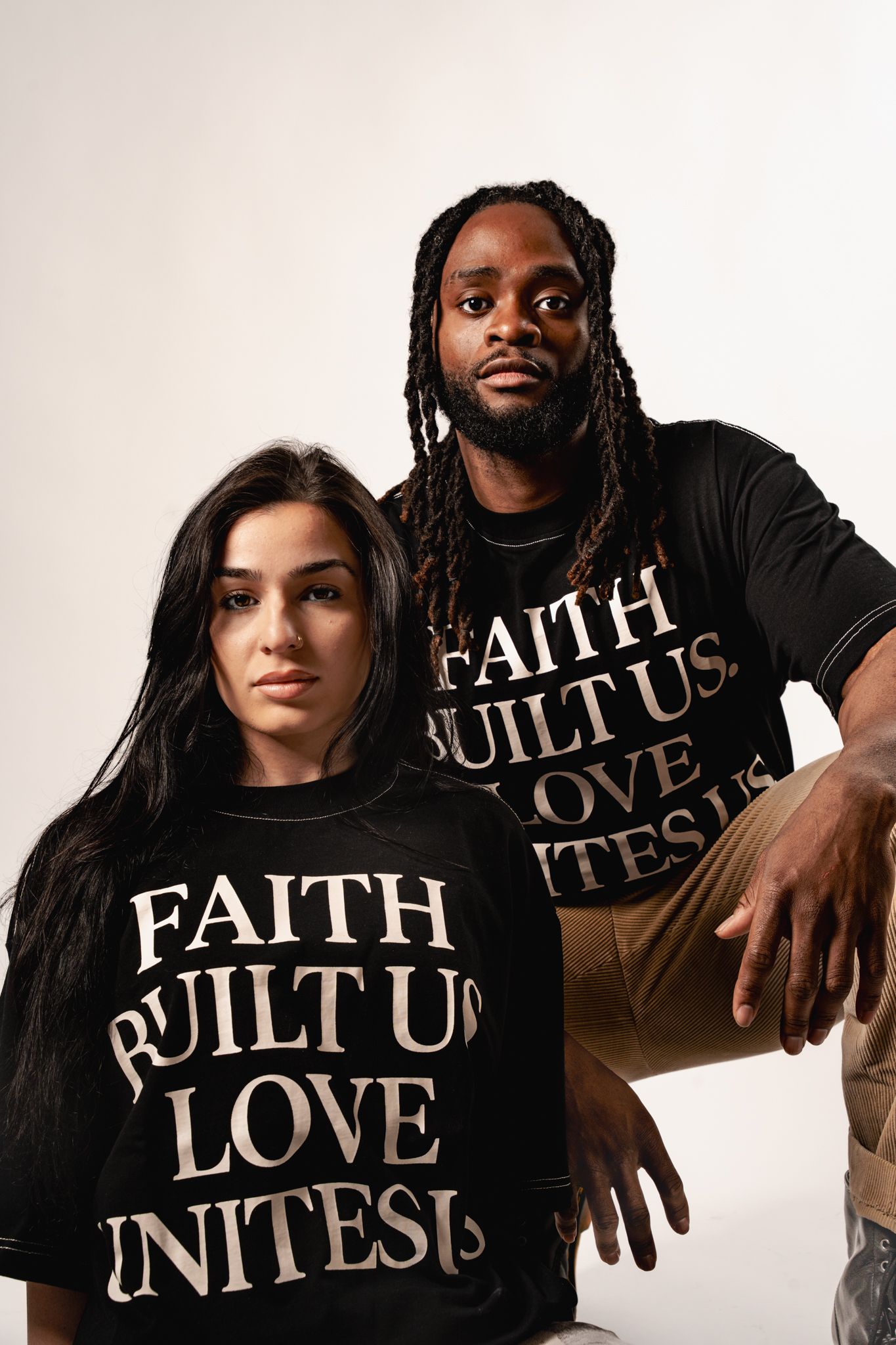 Group photo showing models wearing black t-shirts with text about faith and love against a white background.