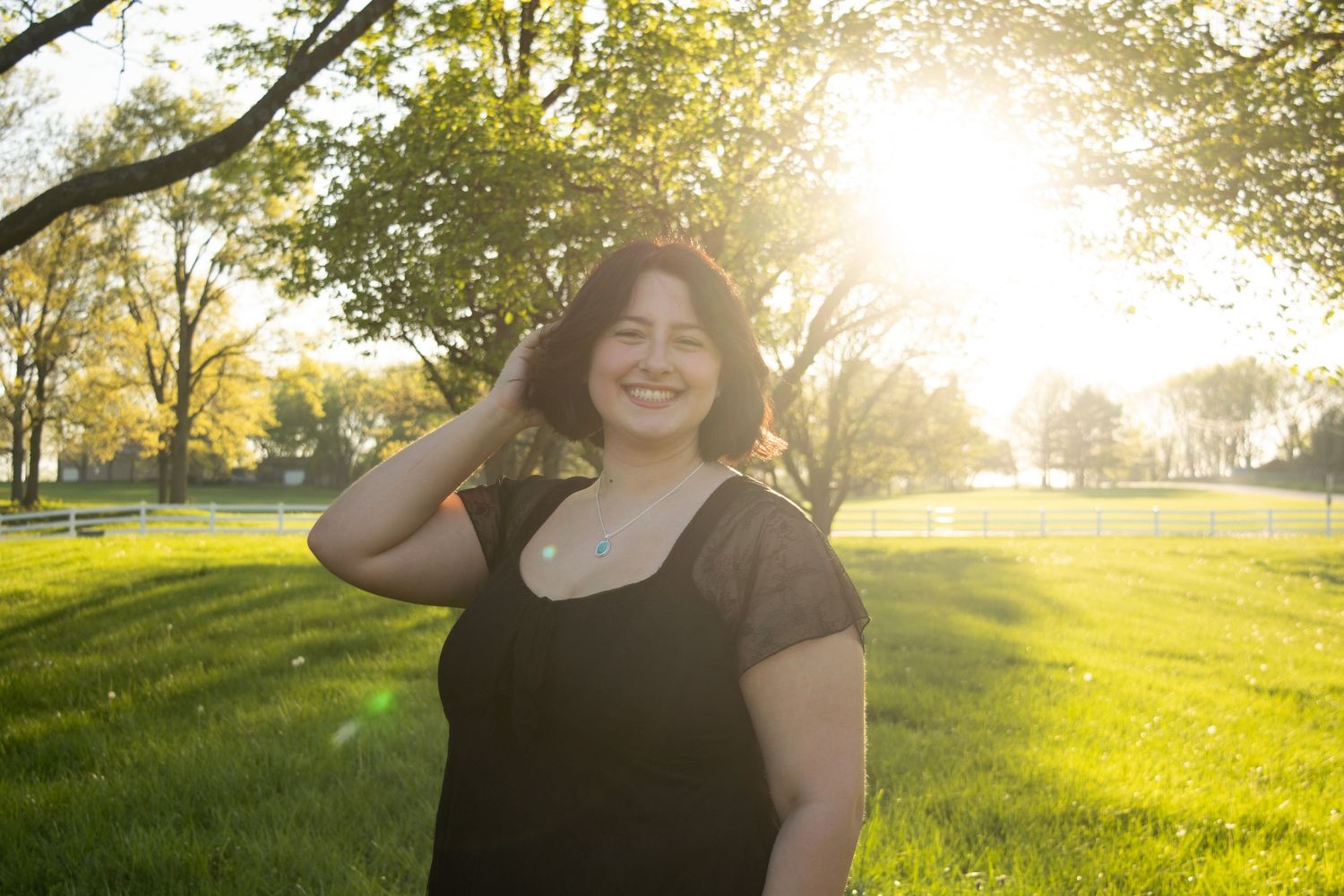 Girl smiling and playing with hair in a field at sunset