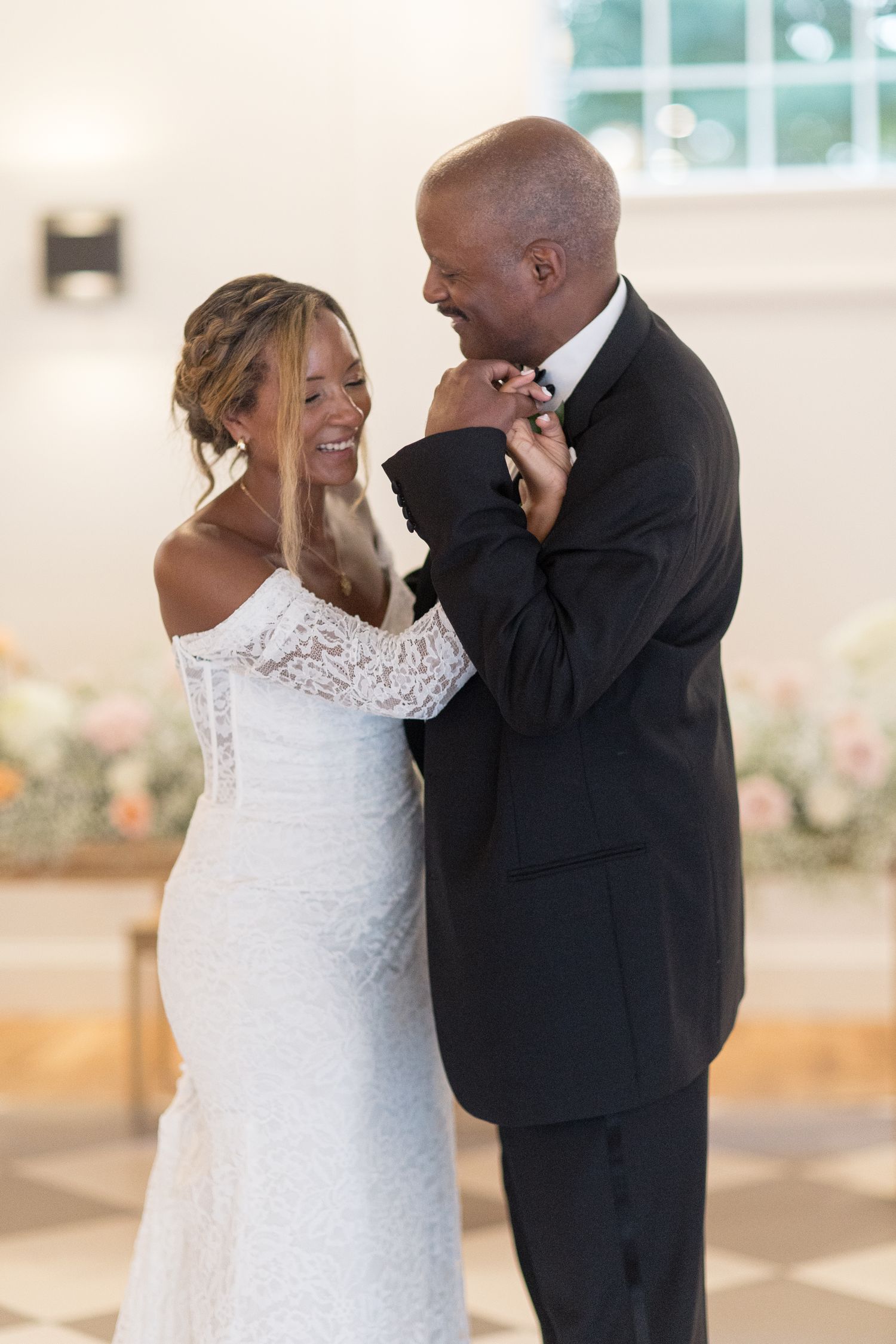 A couple sharing joyful reactions during their first look moment at a bright indoor wedding venue.