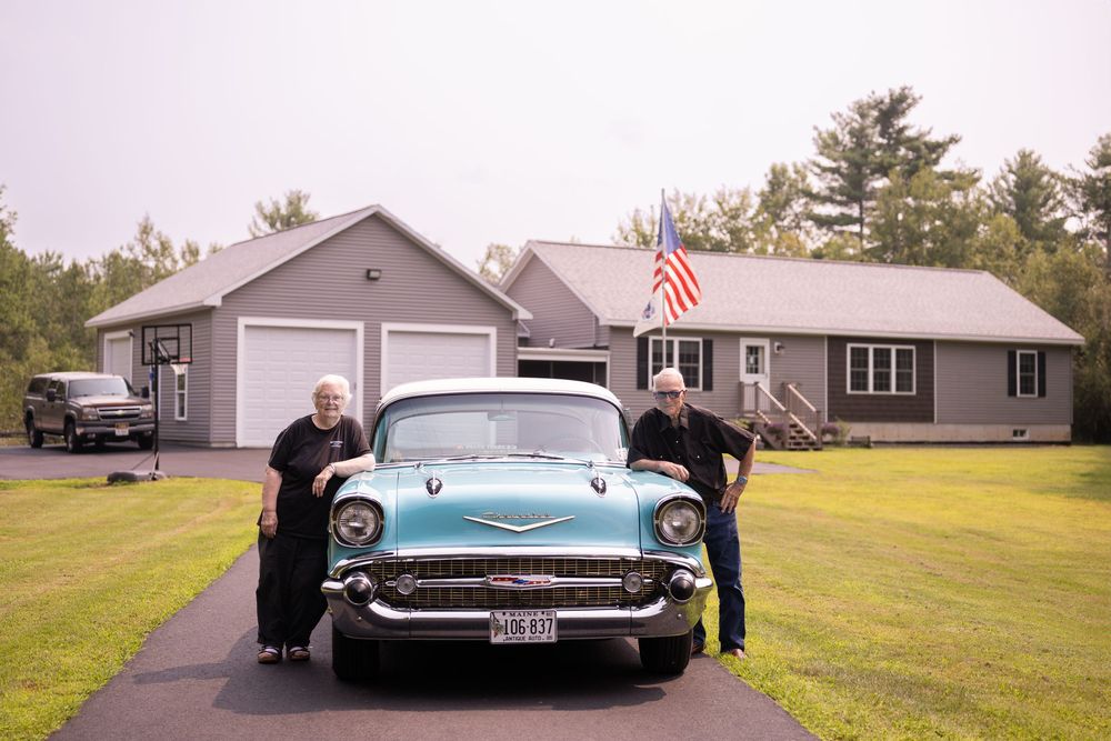 Vintage Chevrolet Bel Air parked in front of residential homes on a cloudy day.