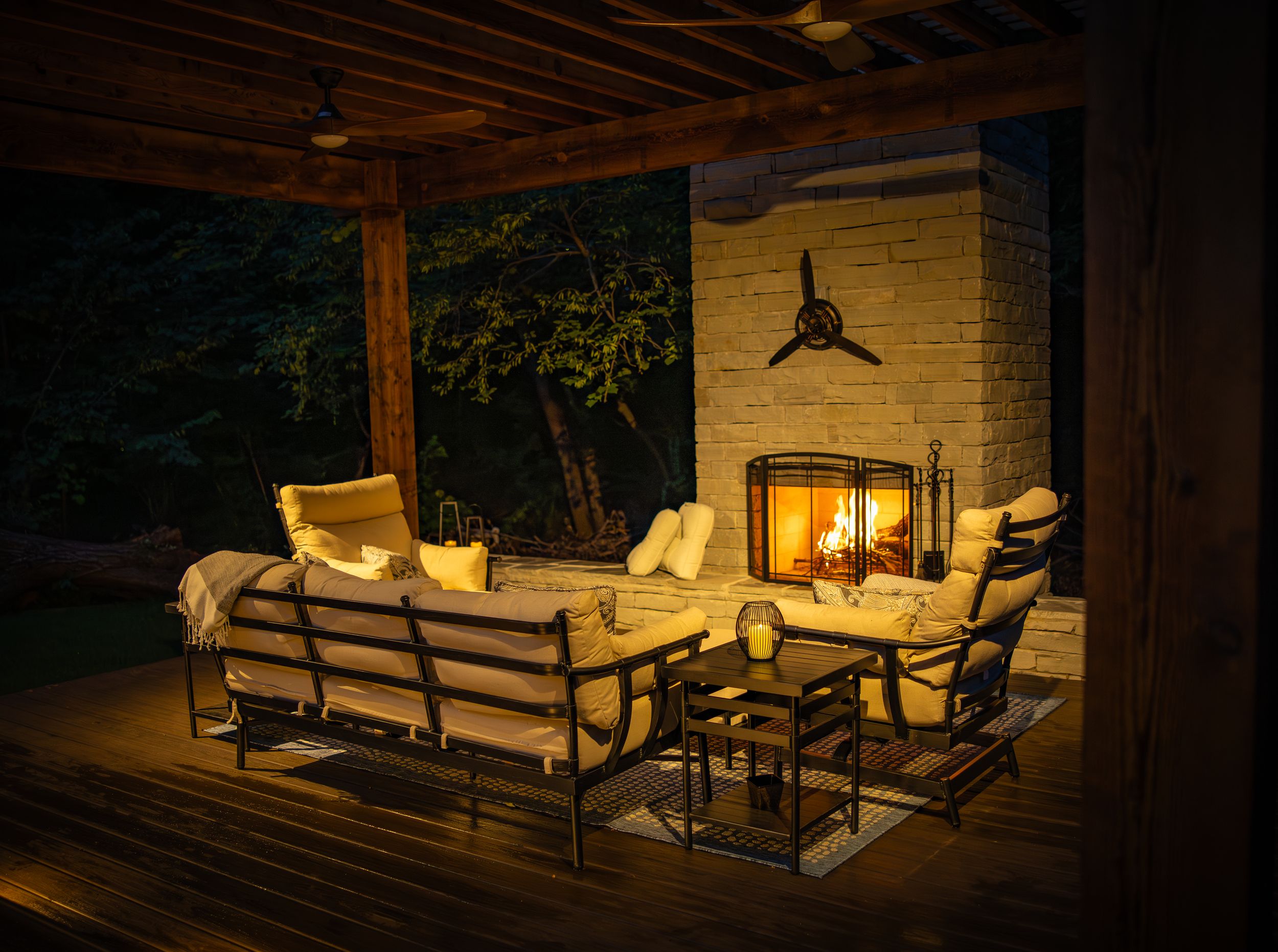 Cozy outdoor patio area illuminated by warm lighting with comfortable seating and hanging lanterns at night.