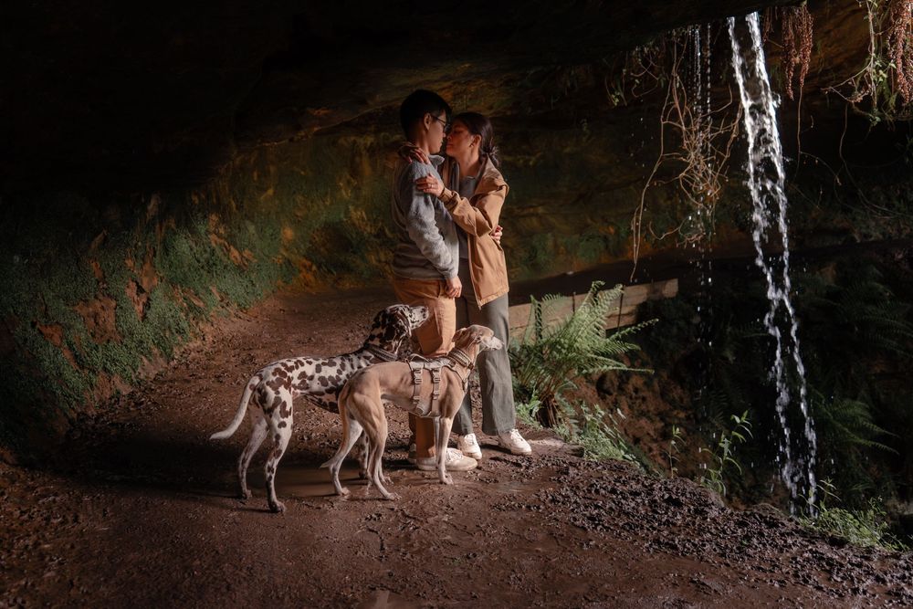 Couple embracing beneath a Scottish waterfall during a relaxed outdoor couples session near Falkland.