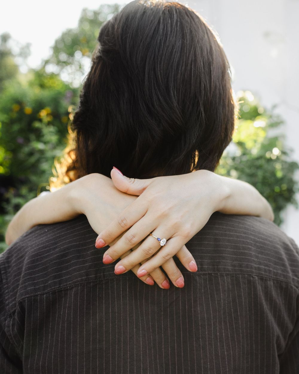 Hands with an engagement ring embracing around shoulders in black and white.