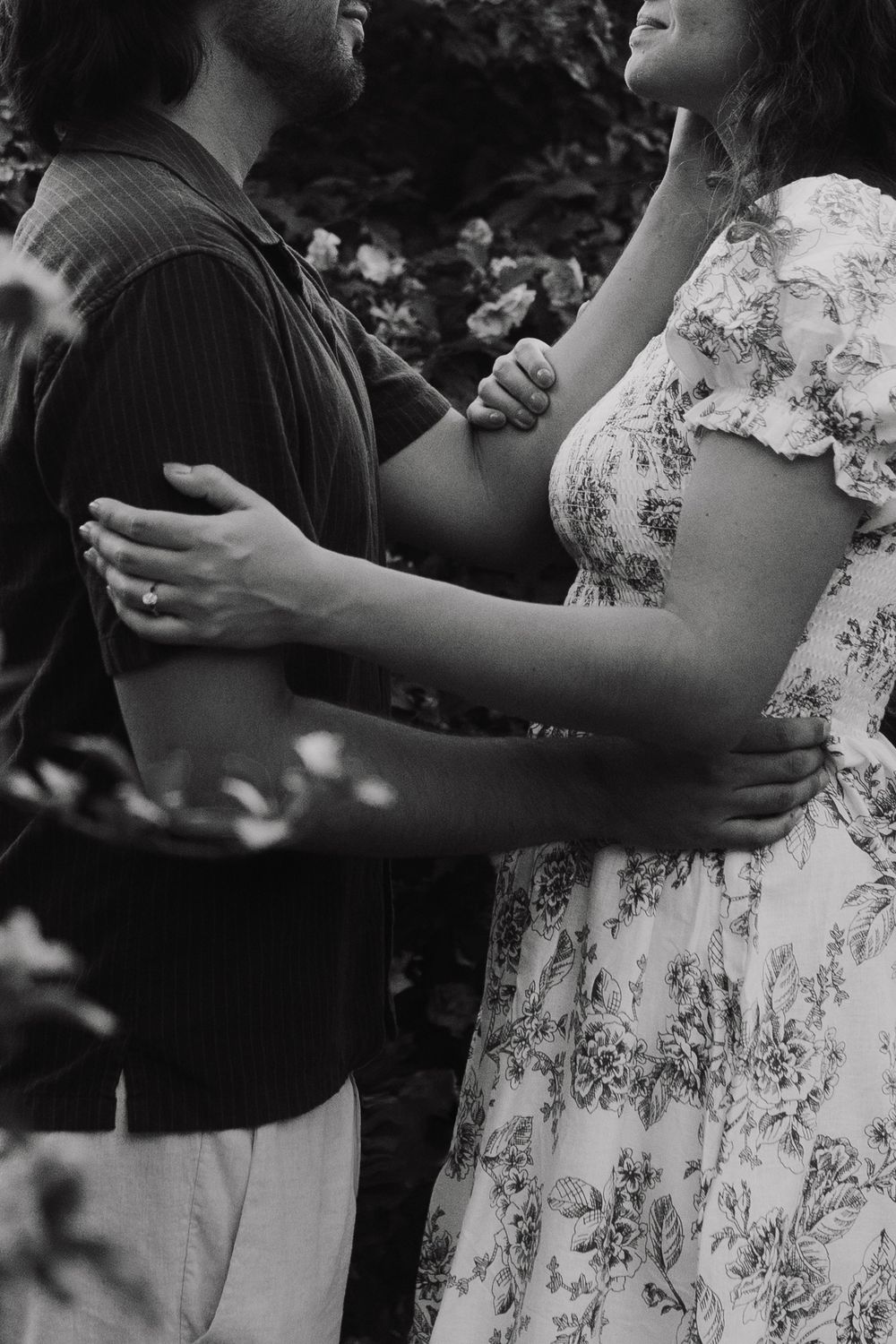 An intimate black and white photograph showing a gentle embrace outdoors.