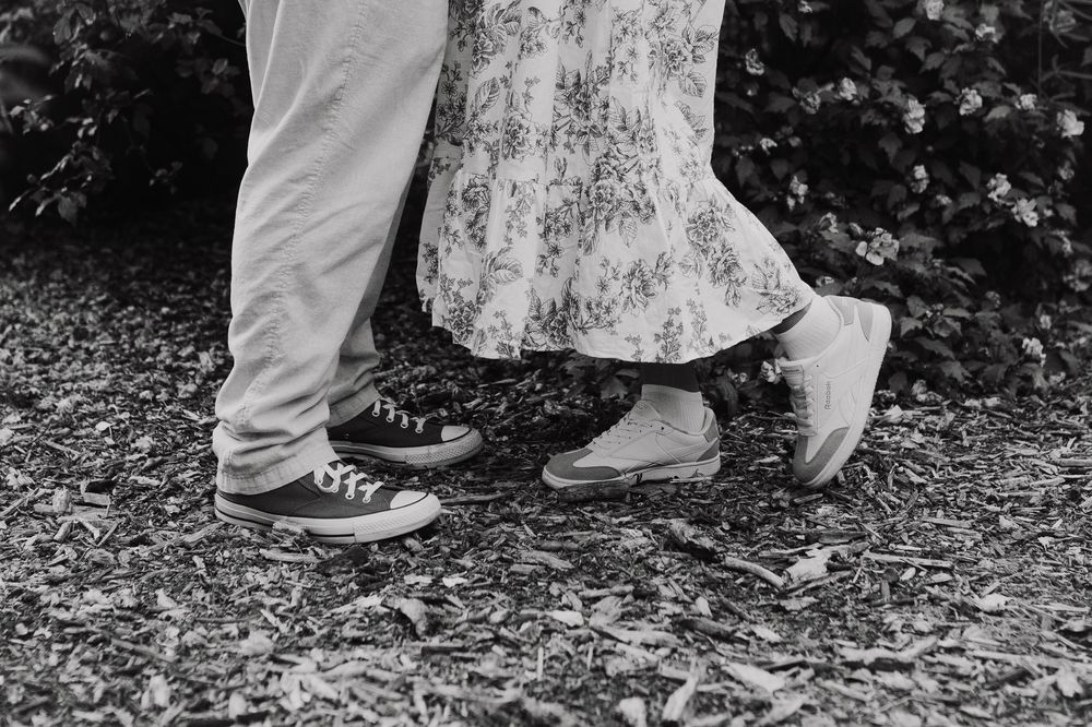 A magical engagement shoot features feet in white shoes walking through fresh grass.