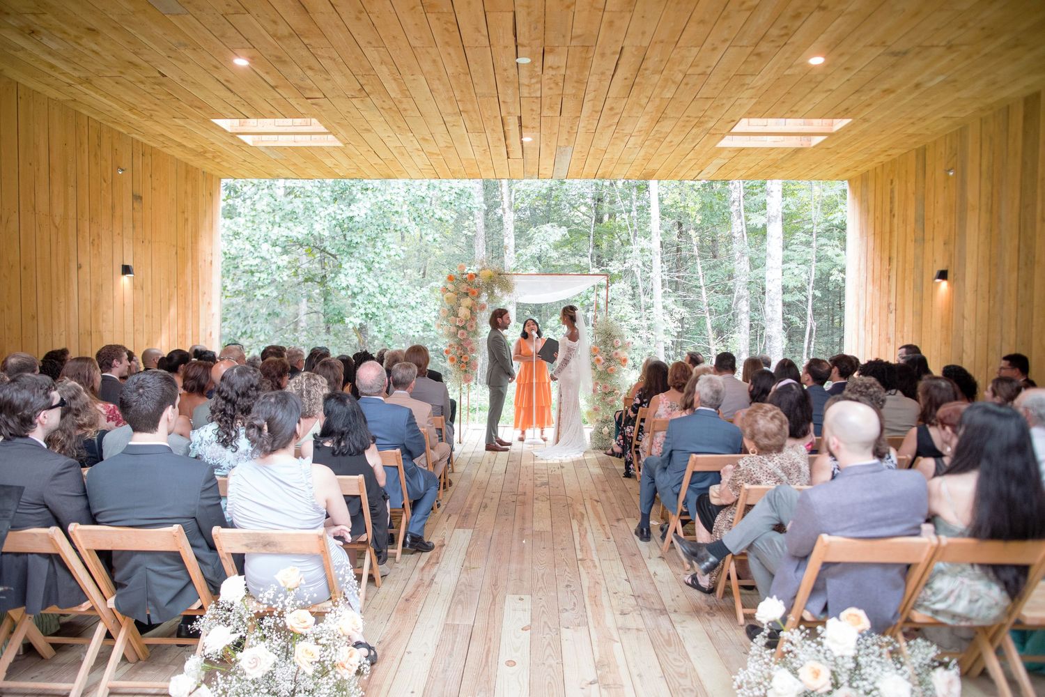 Large groups of attendees seated in rows inside a modern wood-paneled venue for an event.