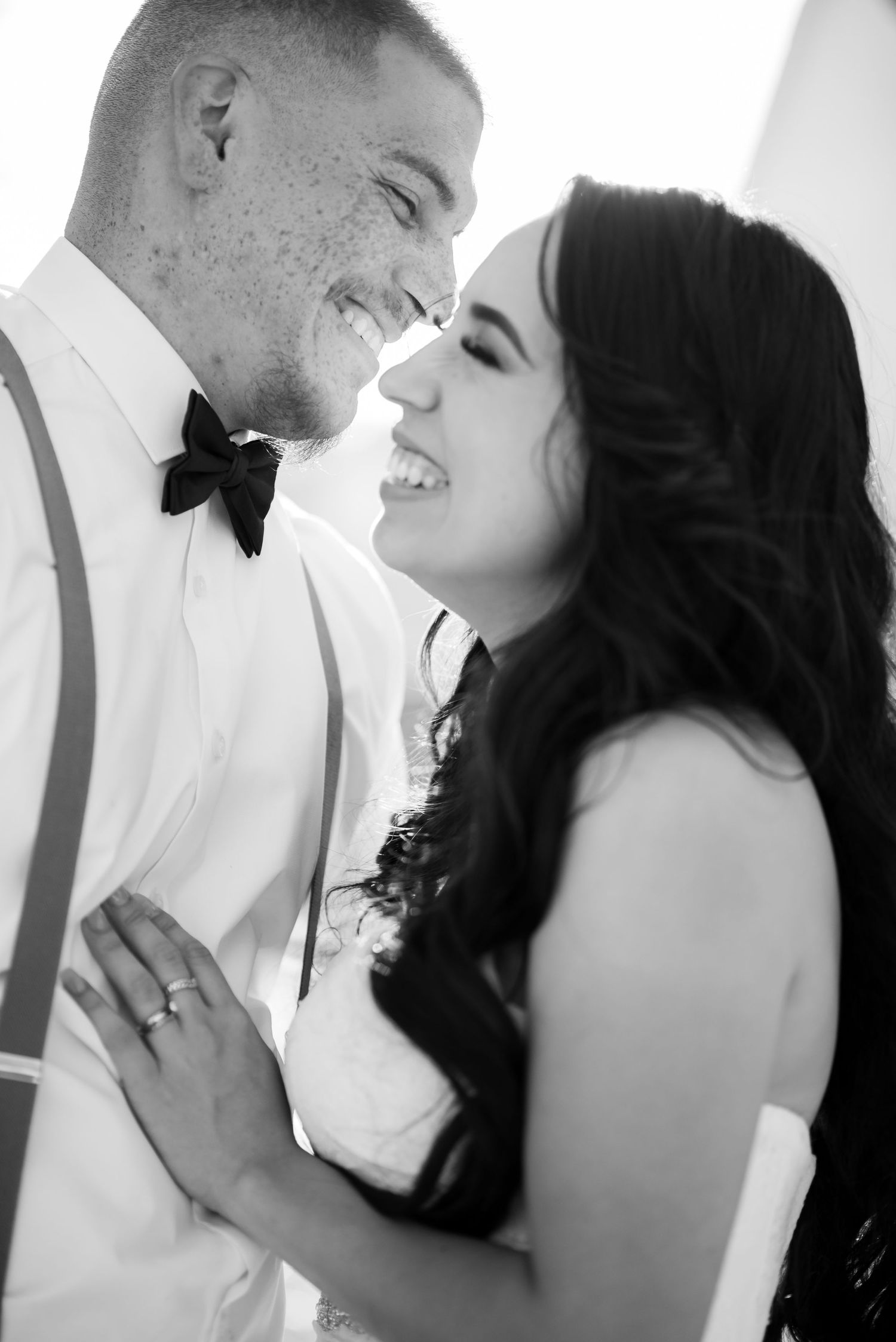 A romantic black and white moment between a couple dressed in formal wedding attire.