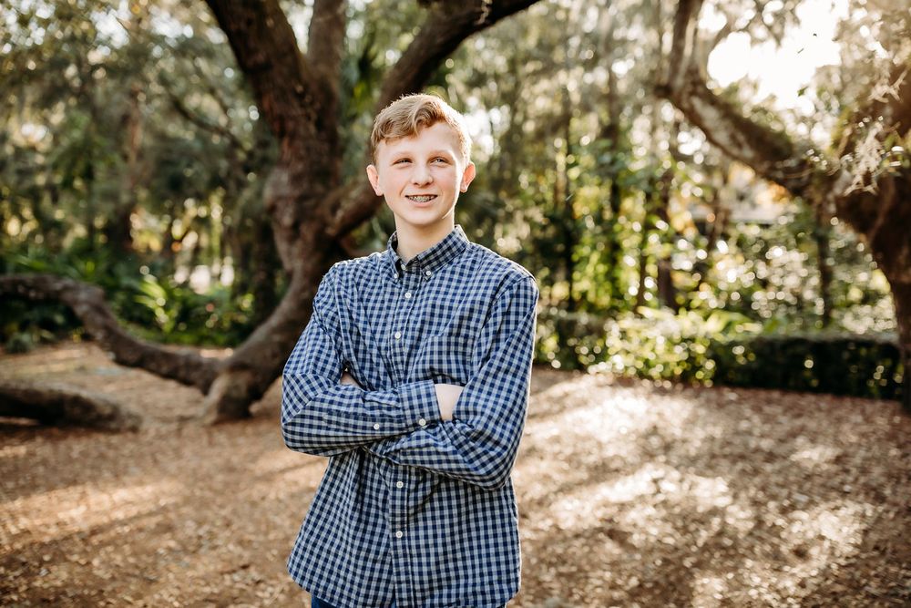 A candid photo session in a sunlit outdoor setting showing a blue checkered shirt against a natural wooded backdrop.
