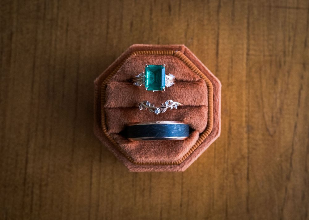 A row of vintage brown leather ring boxes lined up on a wooden surface showing various engagement rings.